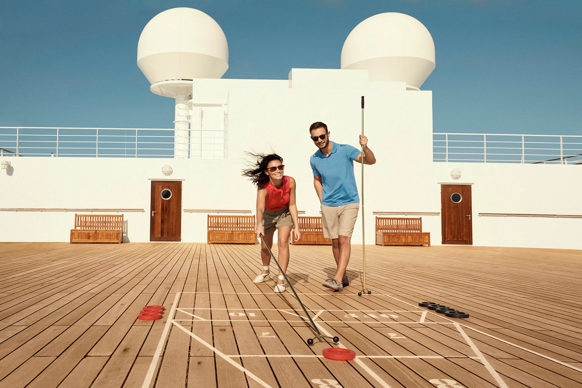 Två personer spelar shuffleboard på ett soldäck. (AI-genererad text)