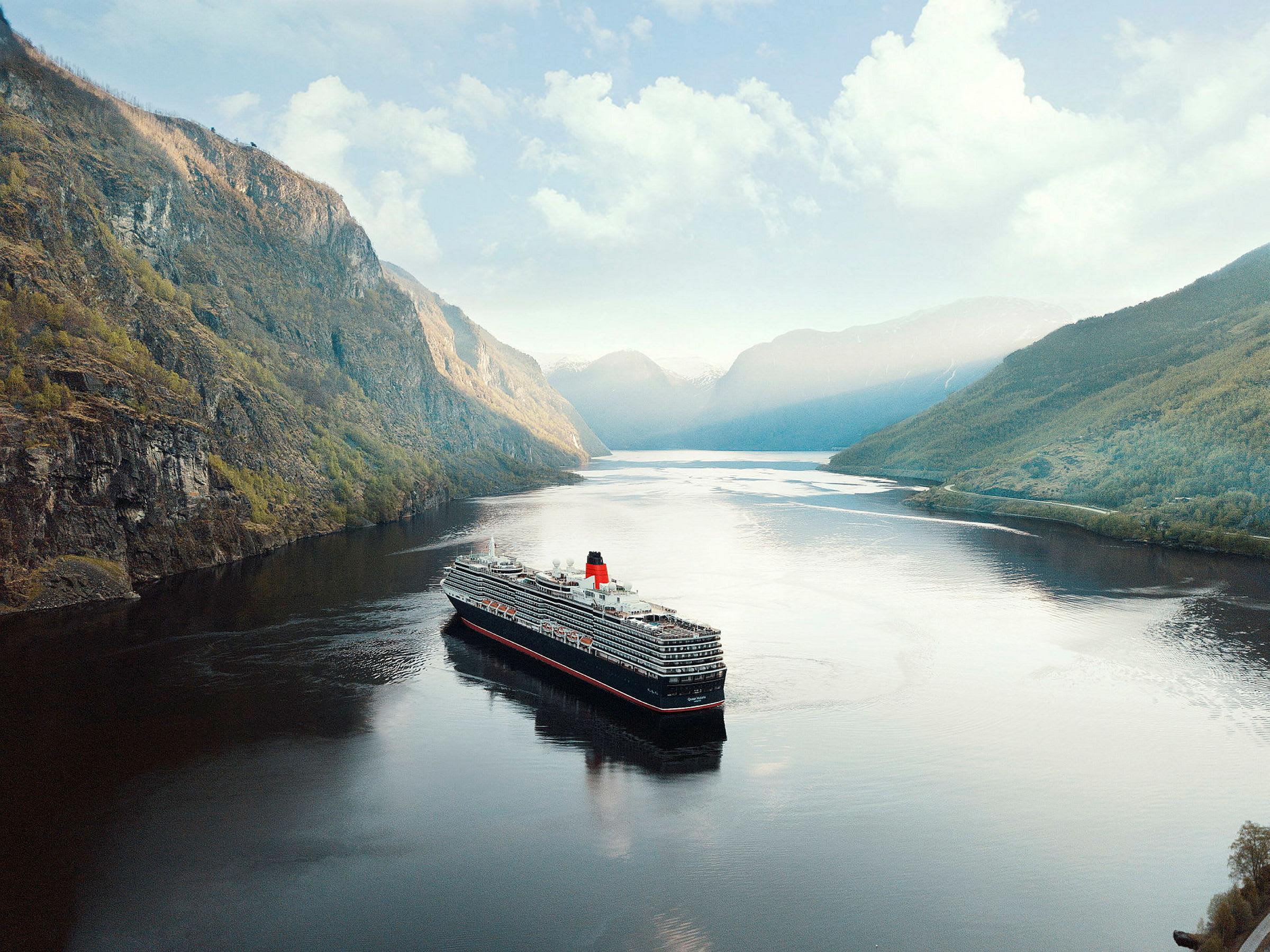 Ett kryssningsfartyg färdas genom en fjord omgiven av höga berg. (AI-genererad text)