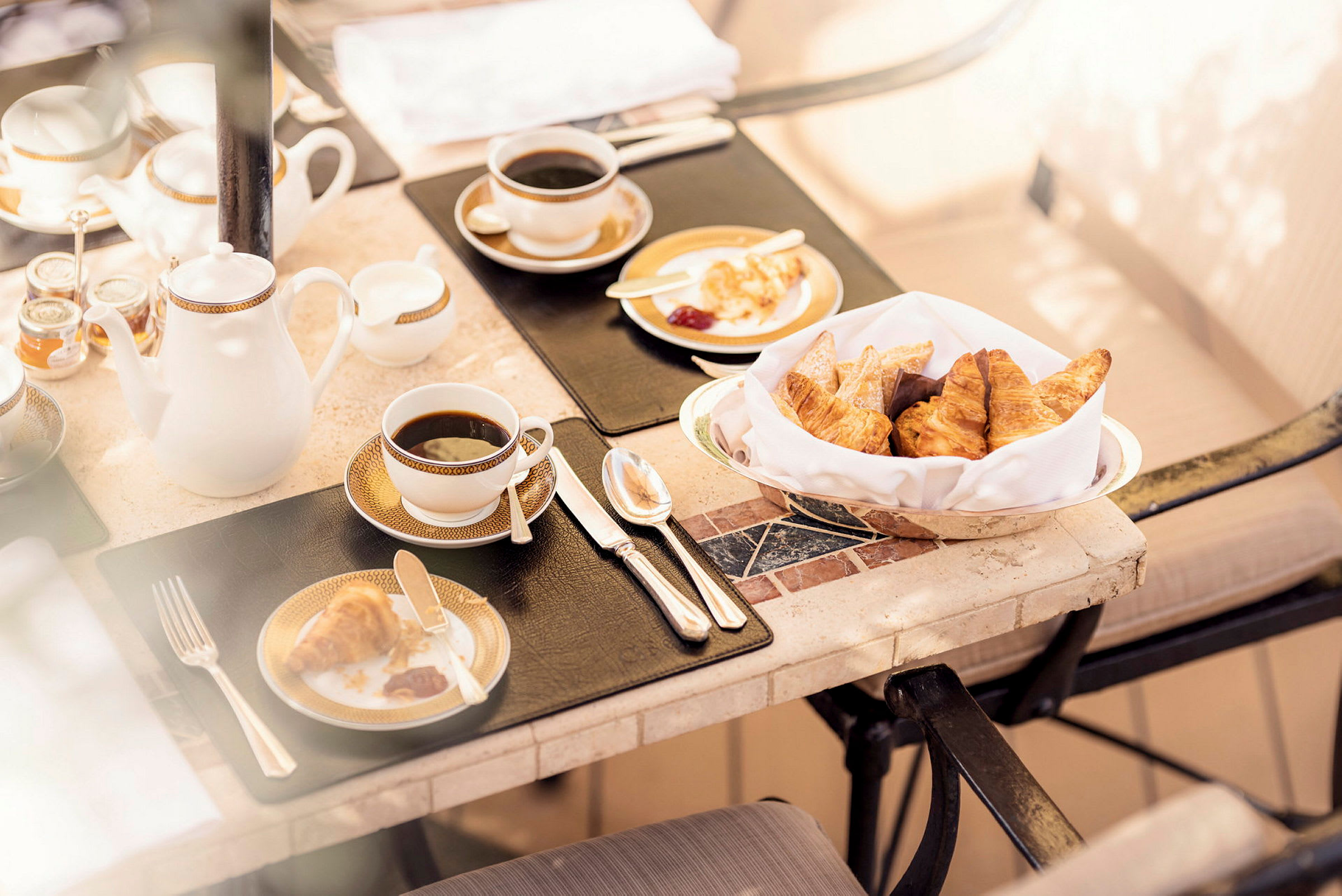 Frukostbord med kaffe, croissanter och marmelad serverade på porslin. (AI-genererad text)