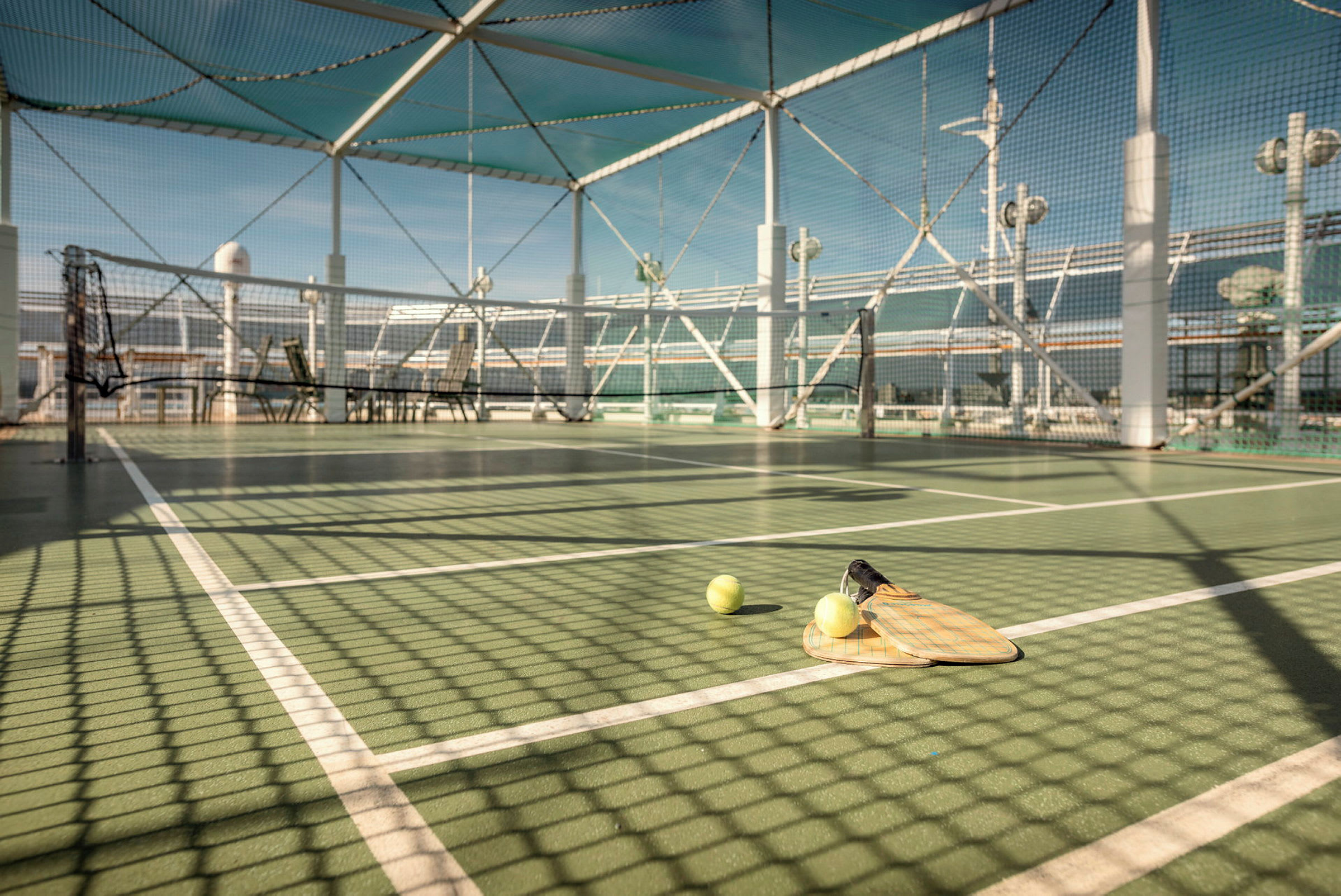 En tennisplan med nät, två bollar och racketar som ligger på marken. (AI-genererad text)