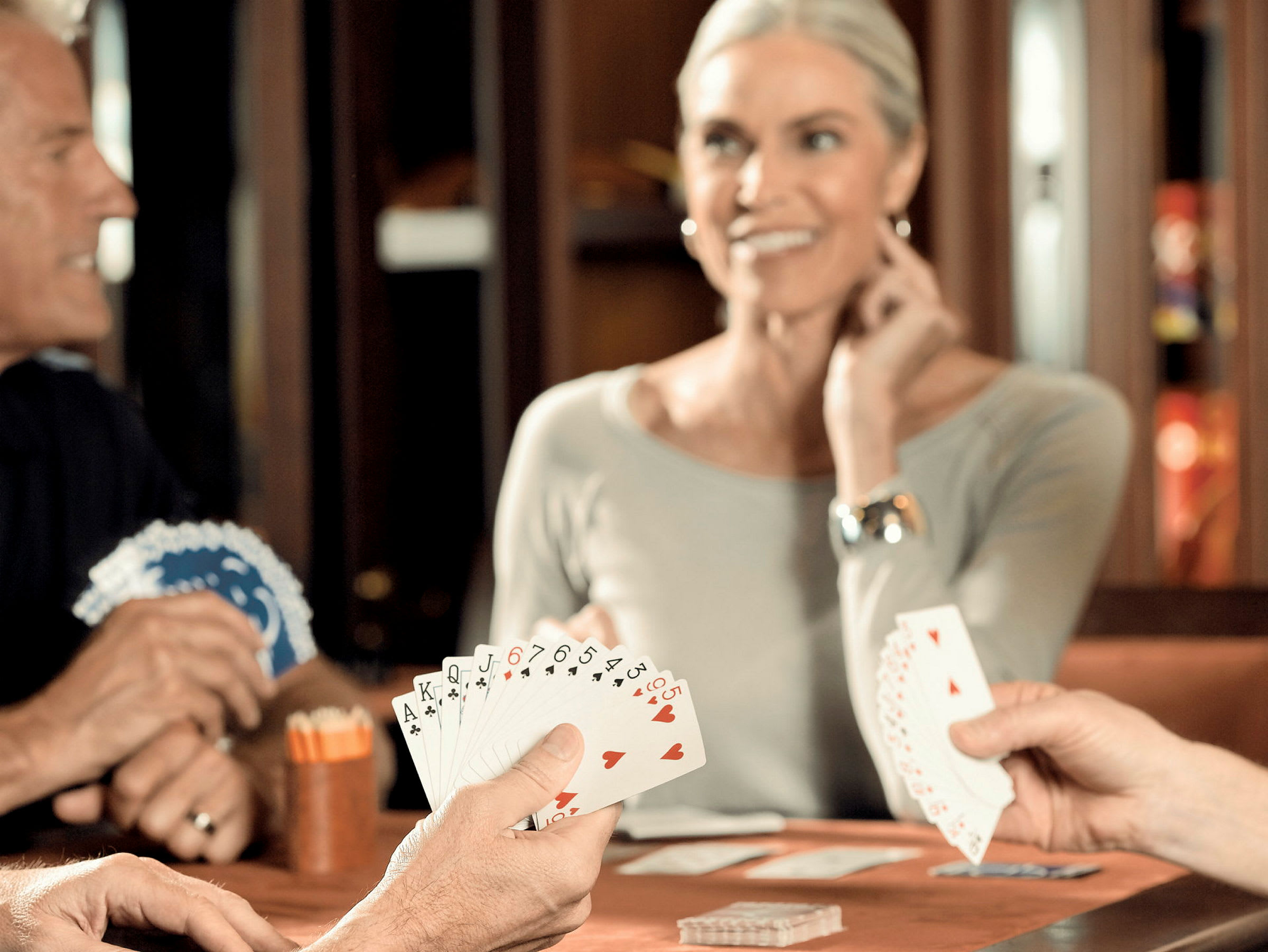 Tre personer som spelar kortspel vid ett bord. (AI-genererad text)