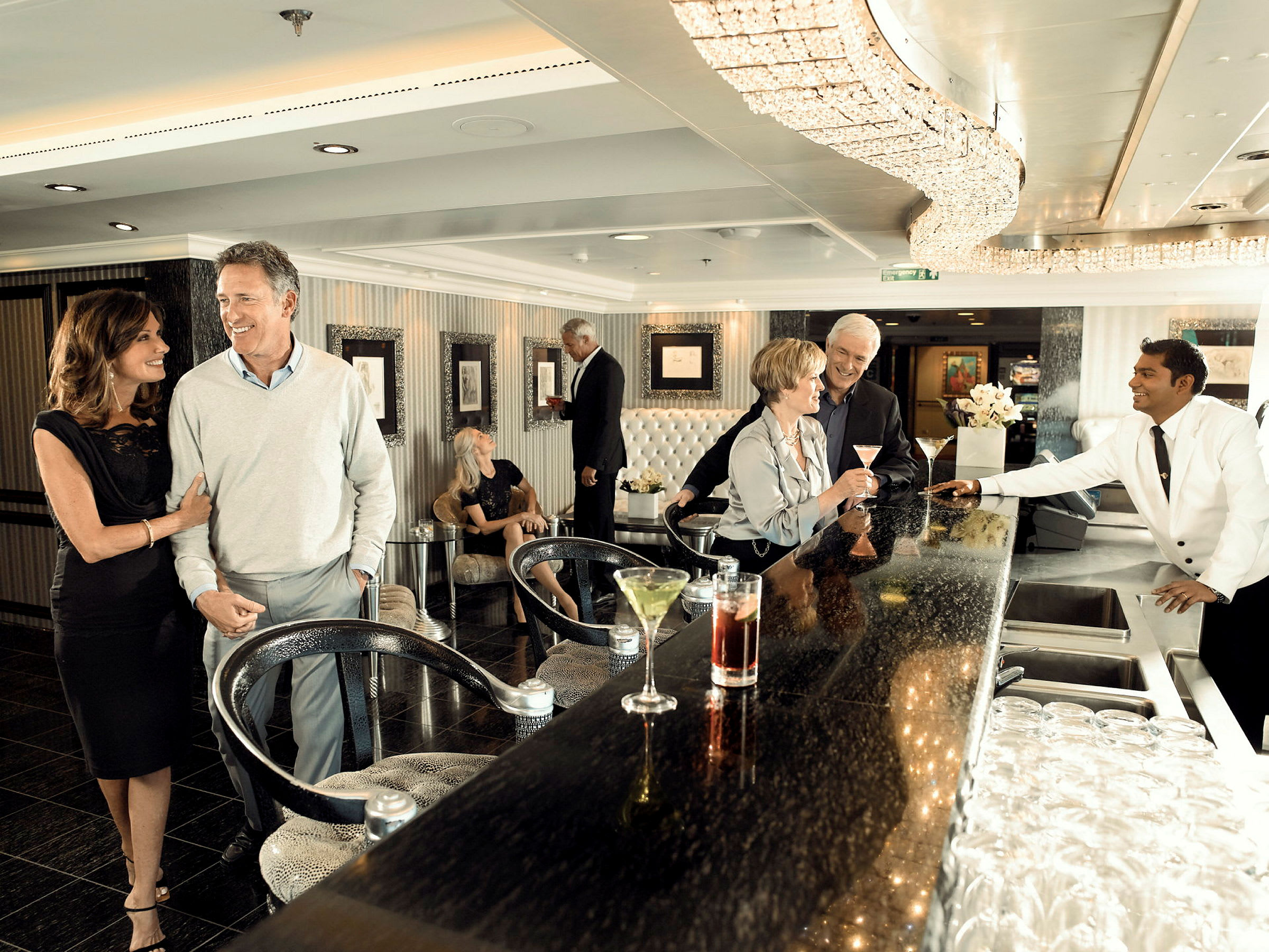 Personer samlade i en modern bar med eleganta möbler och kristallbelysning. (AI-genererad text)