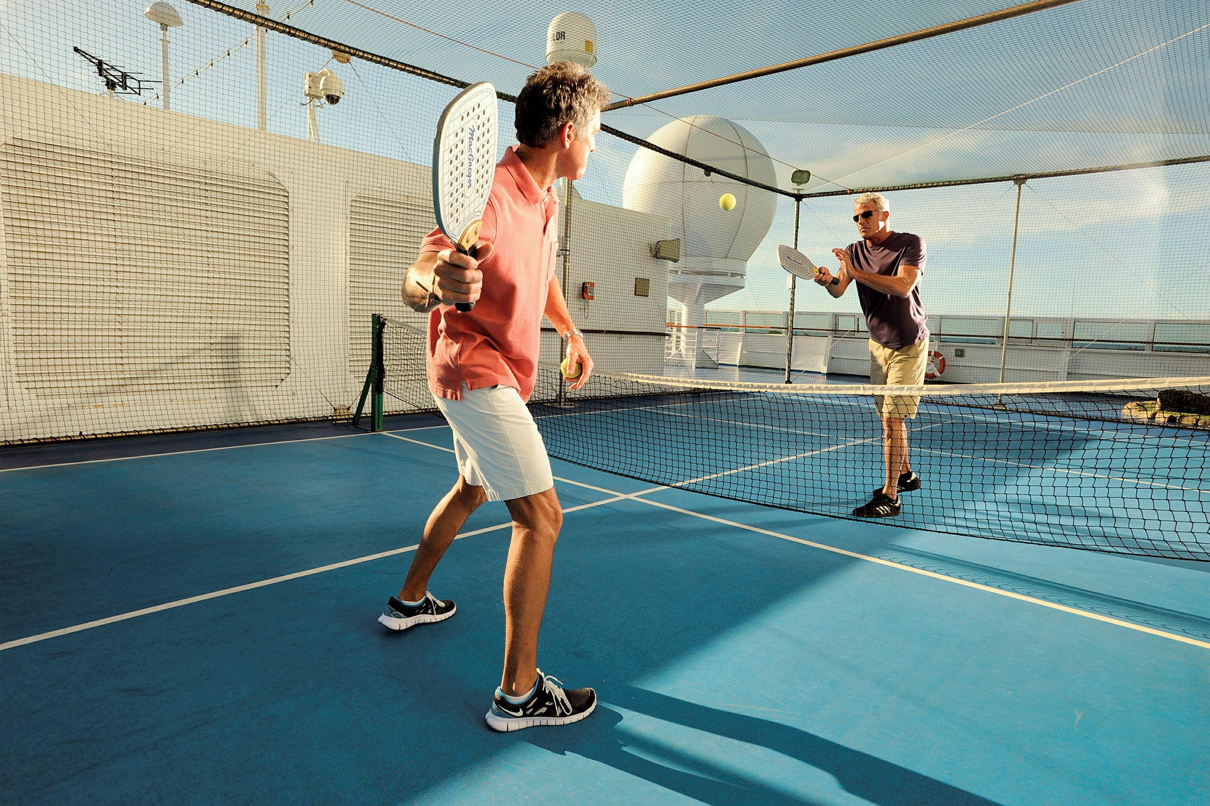 Två personer spelar padel på ett utomhusdäck med nät. (AI-genererad text)