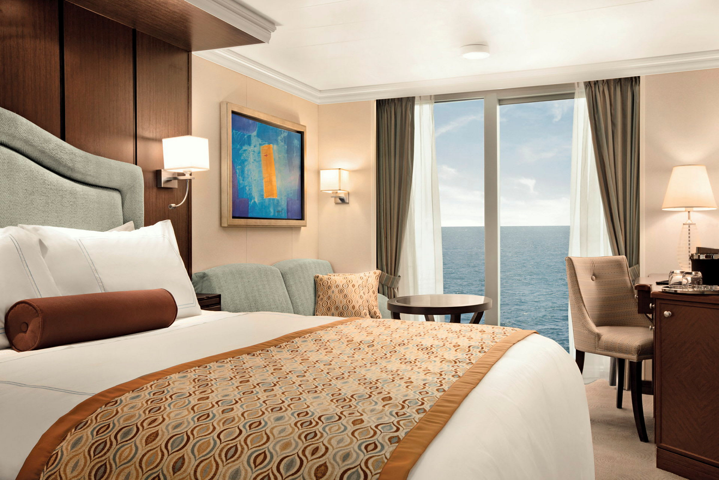 Ett hotellrum med en stor säng, sittgrupp och fönster som visar havet. (AI-genererad text)