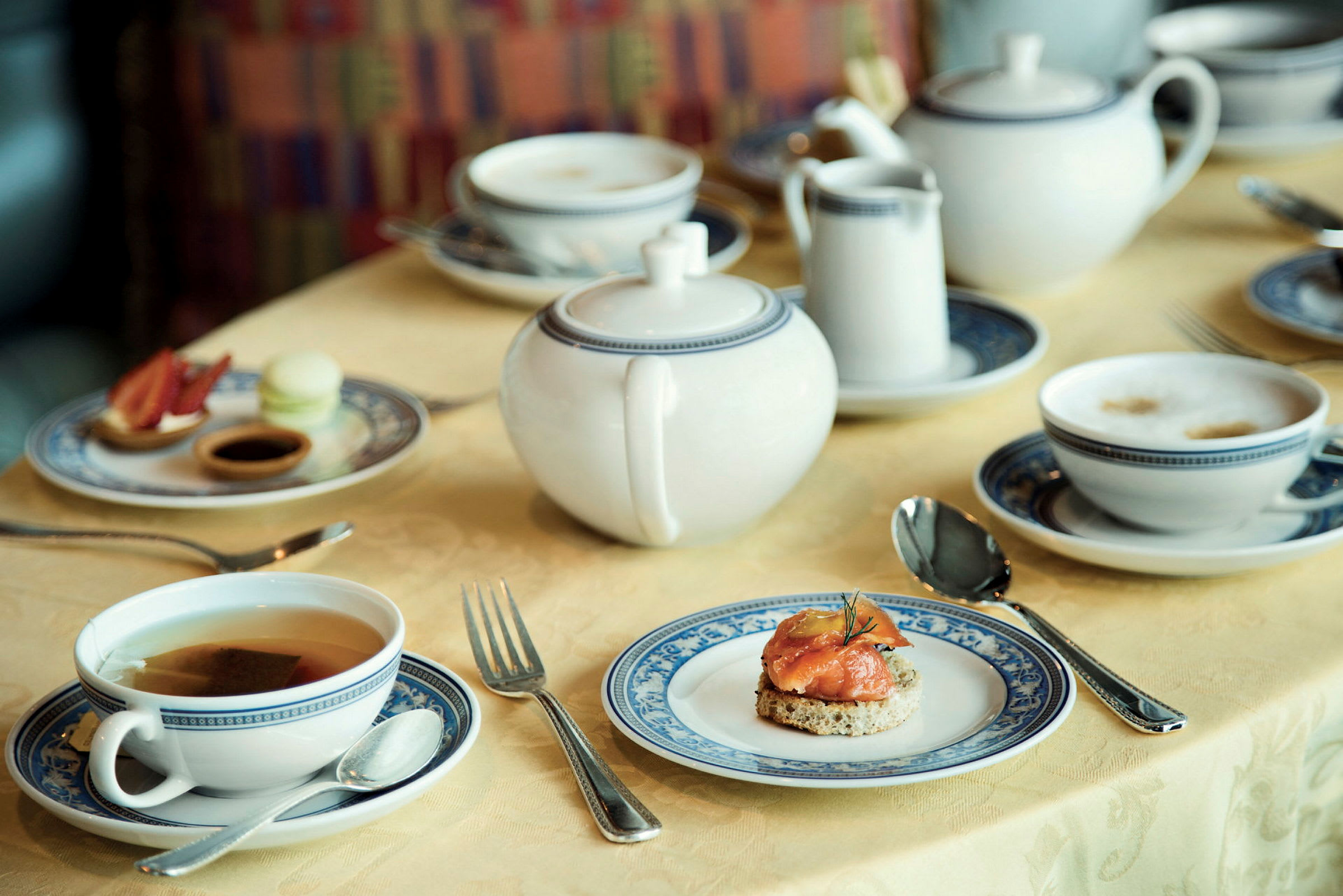 Ett uppdukat bord med te- och kaffeserviser, små tallrikar med olika tilltugg och en tekanna. (AI-genererad text)