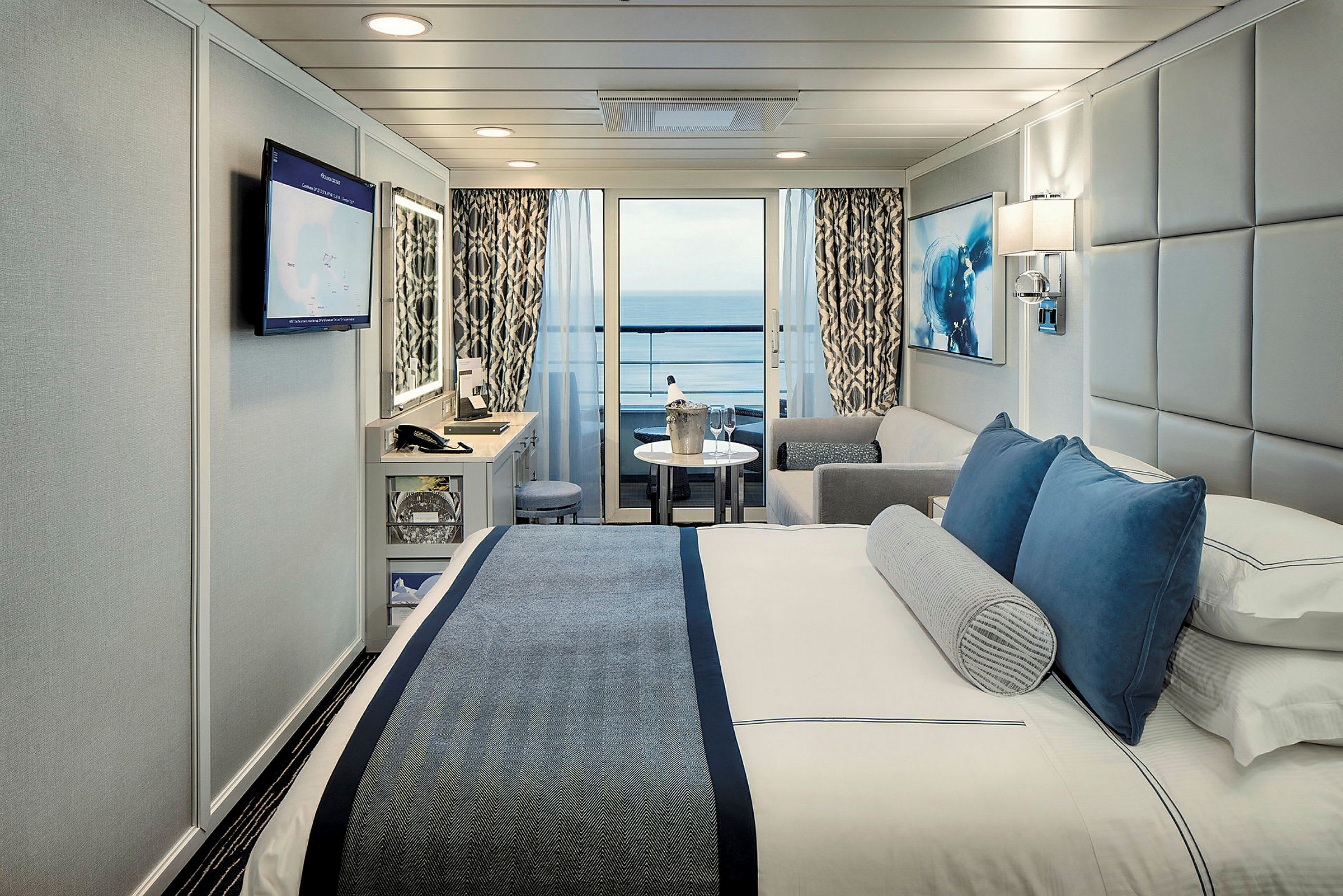 Hotellrum med säng, soffa, tv och balkong med havsutsikt. (AI-genererad text)
