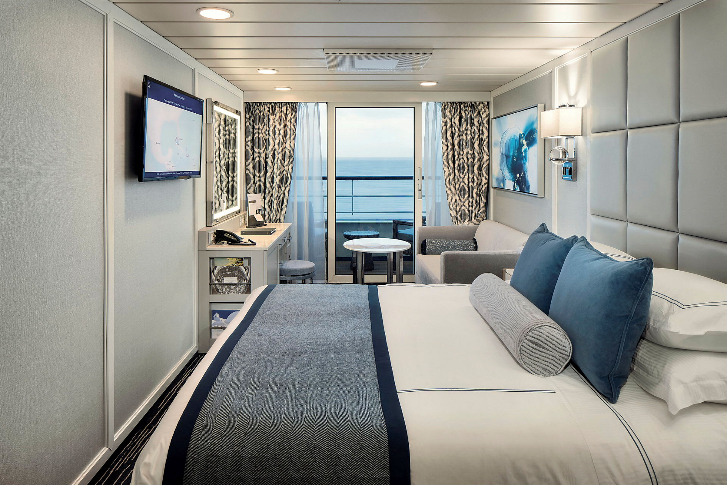 Ett modernt hotellrum med en dubbelsäng, soffa och en balkong med havsutsikt. (AI-genererad text)