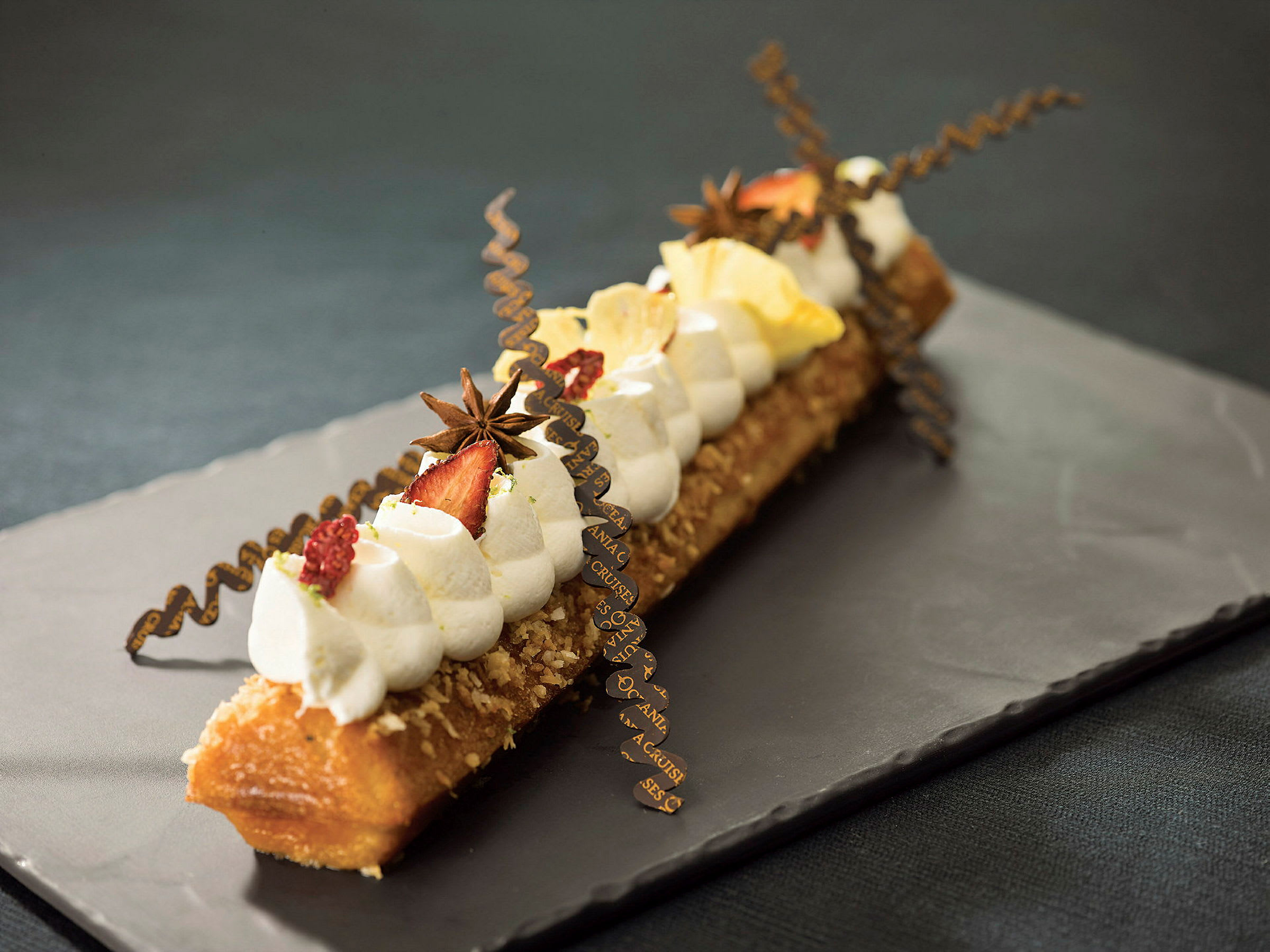 Dekorerad dessert serverad på en mörk tallrik. (AI-genererad text)