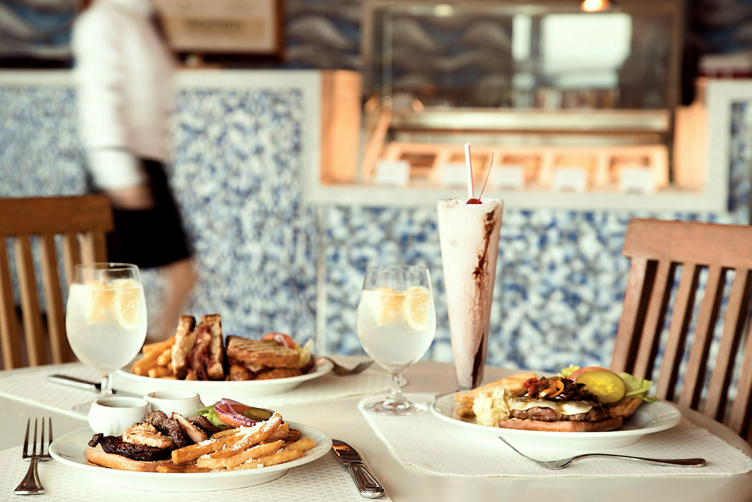 Ett bord med olika rätter, inklusive hamburgare, pommes frites och en milkshake. (AI-genererad text)