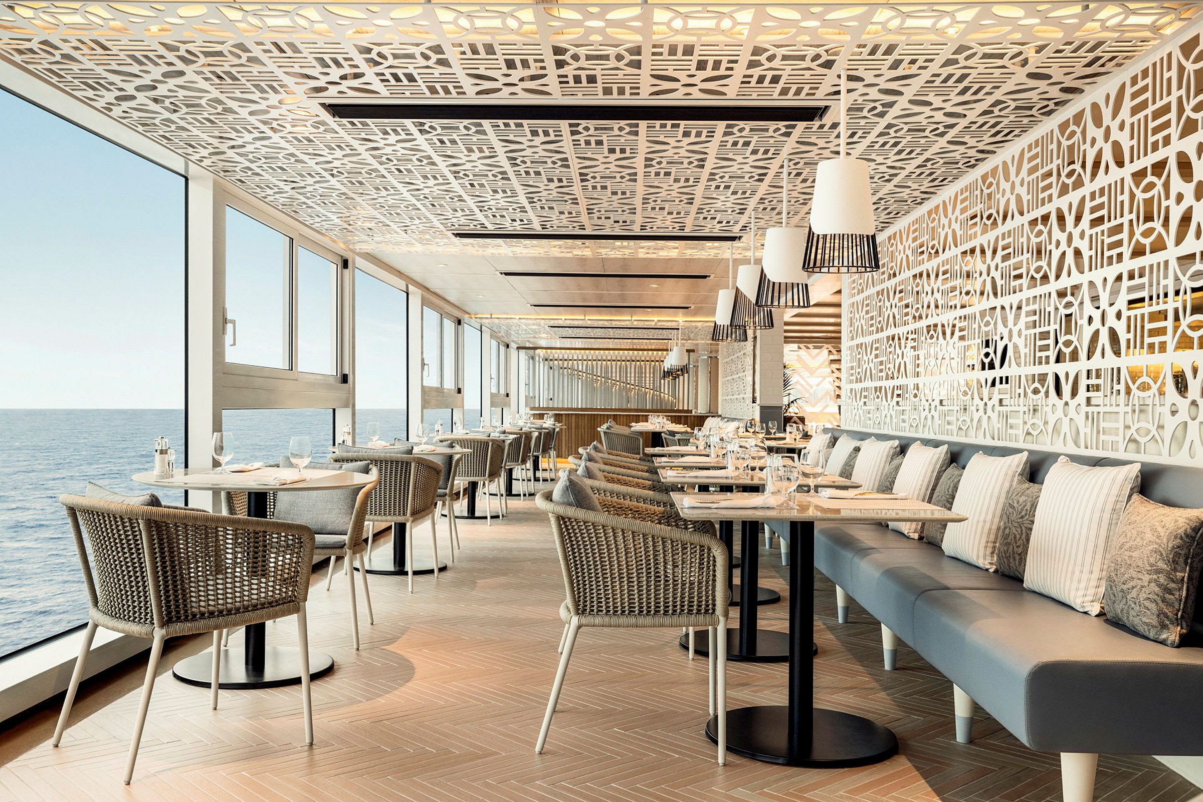 Restaurang med bord, stolar och utsikt mot havet genom stora fönster. (AI-genererad text)