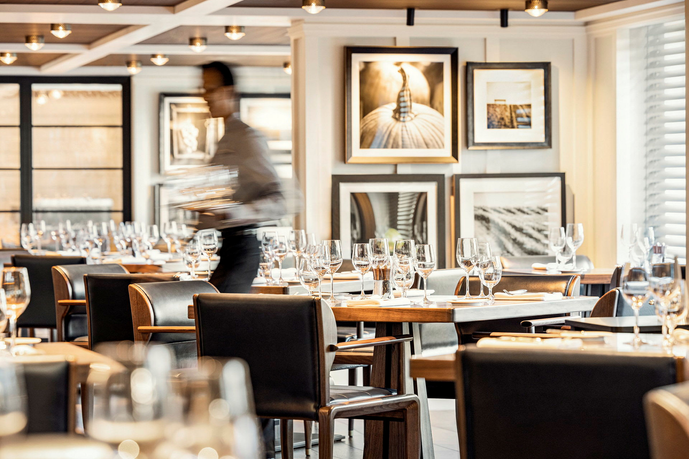 En elegant restaurang med dukade bord och glas, med konstverk på väggen. (AI-genererad text)