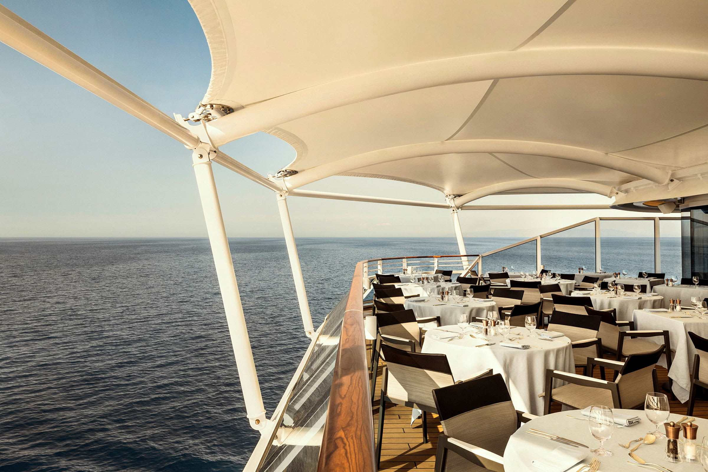 Utomhus serveringsområde med vit dukning och utsikt över havet. (AI-genererad text)