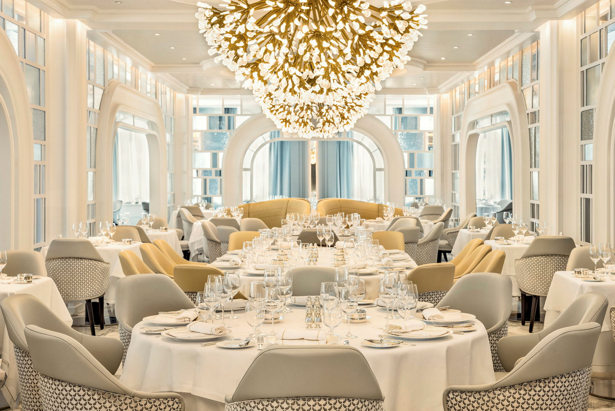 En elegant restaurang med vita dukar och en stor ljuskrona. (AI-genererad text)