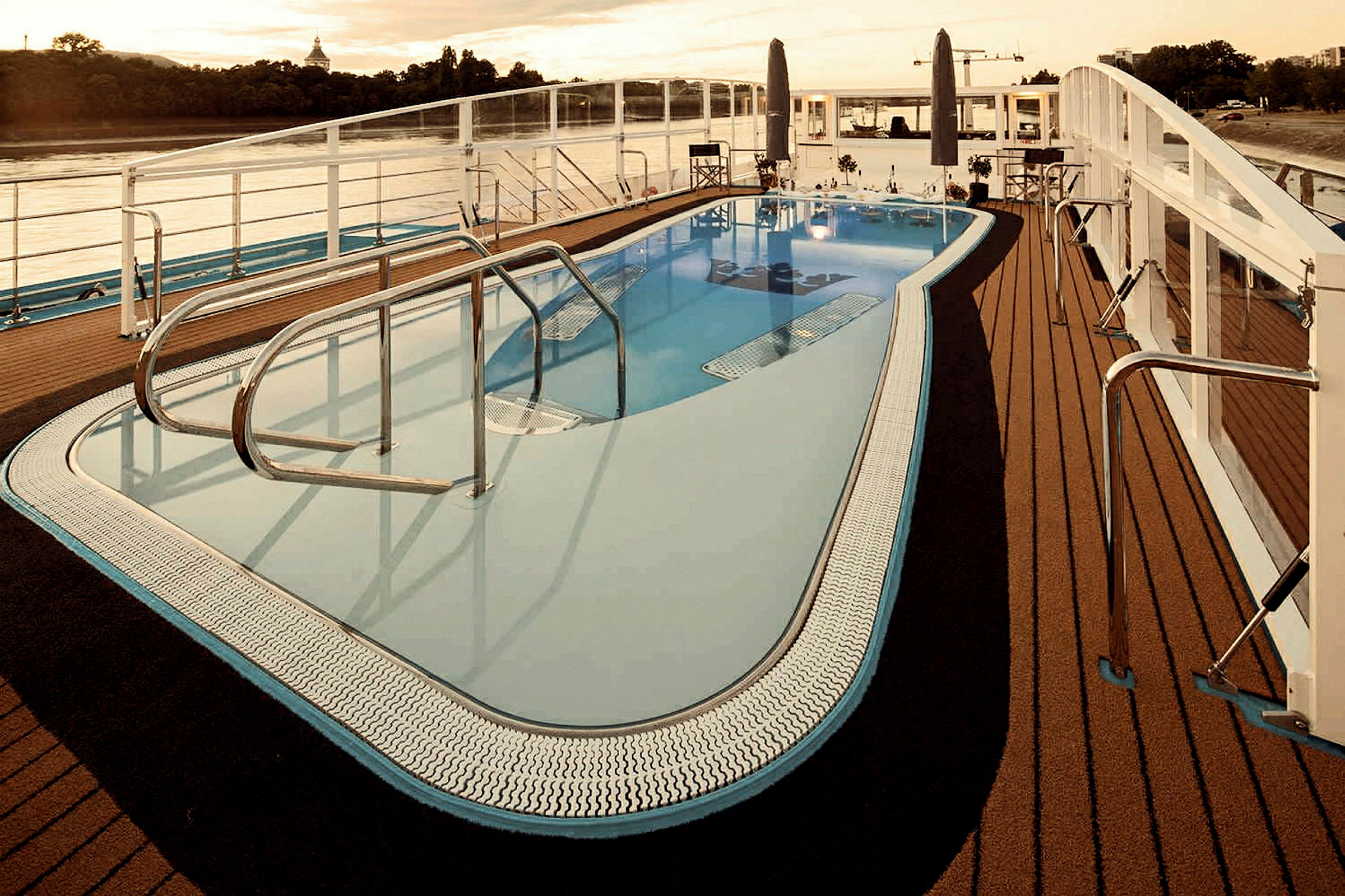 Pool med stålräcken omgiven av bryggor nära vattnet vid solnedgång. (AI-genererad text)