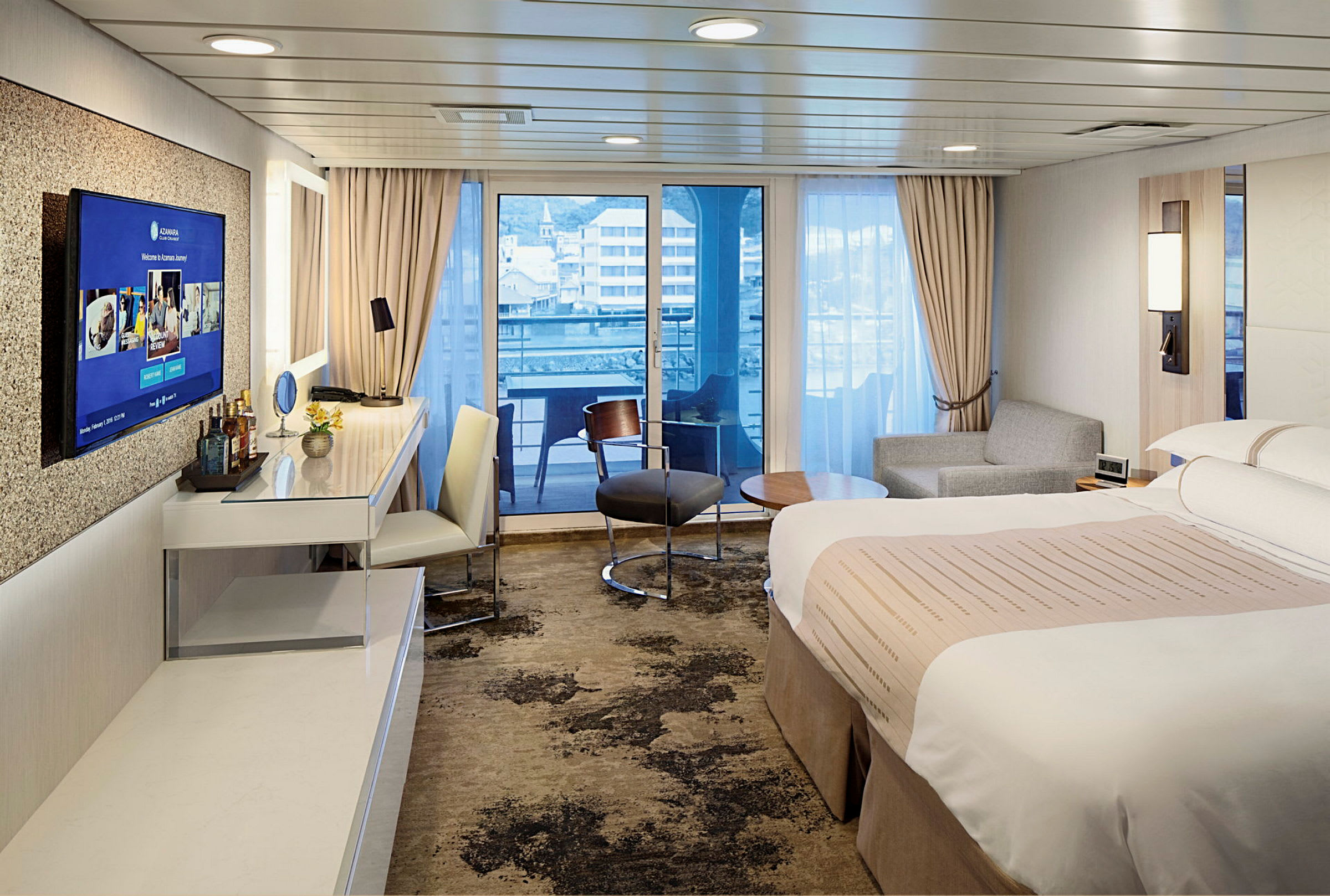 Hotellrum med säng, skrivbord, sittgrupp och utsikt mot balkong och stad. (AI-genererad text)