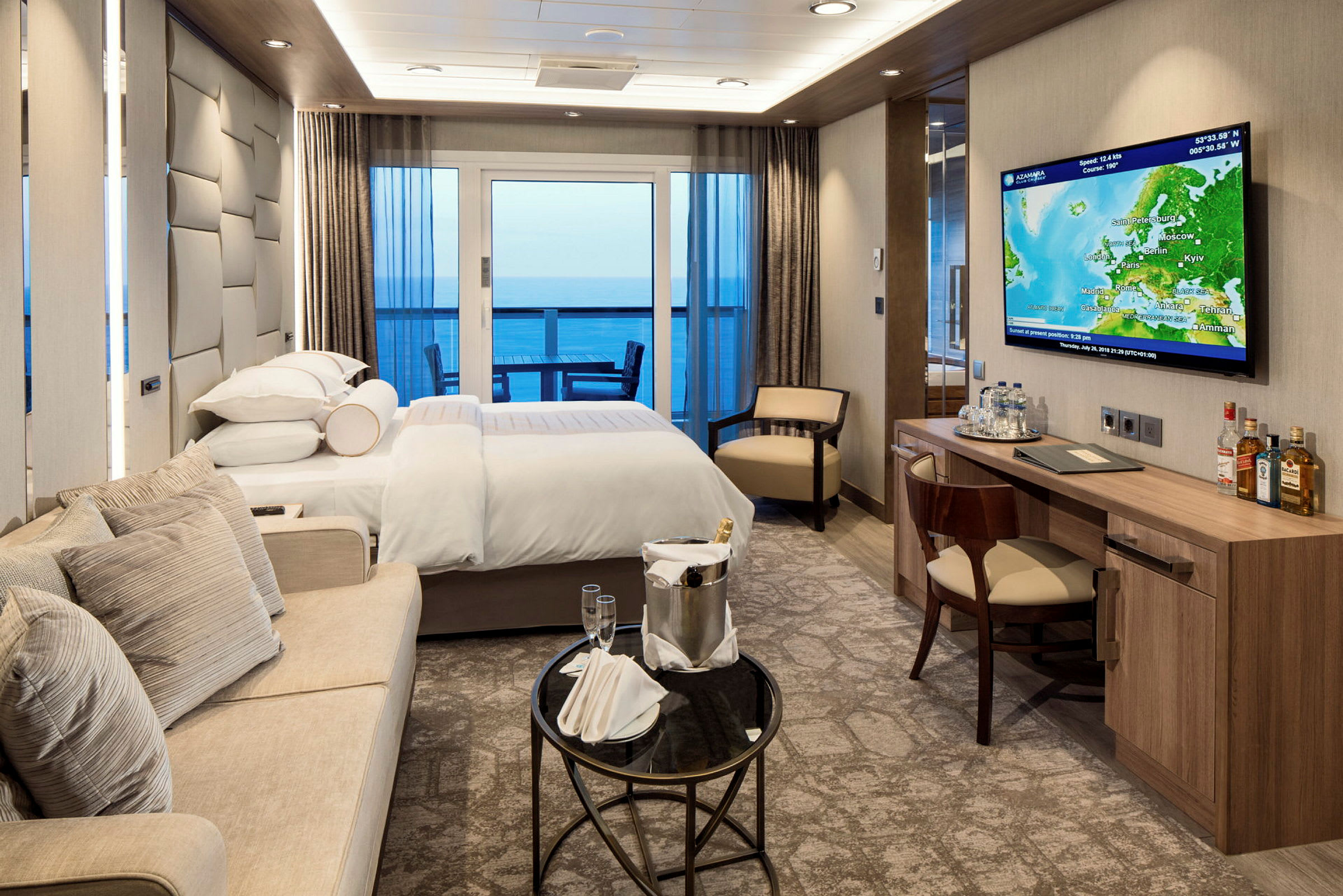 Hotellrum med dubbelsäng, sittgrupp, skrivbord och utsikt över havet. (AI-genererad text)