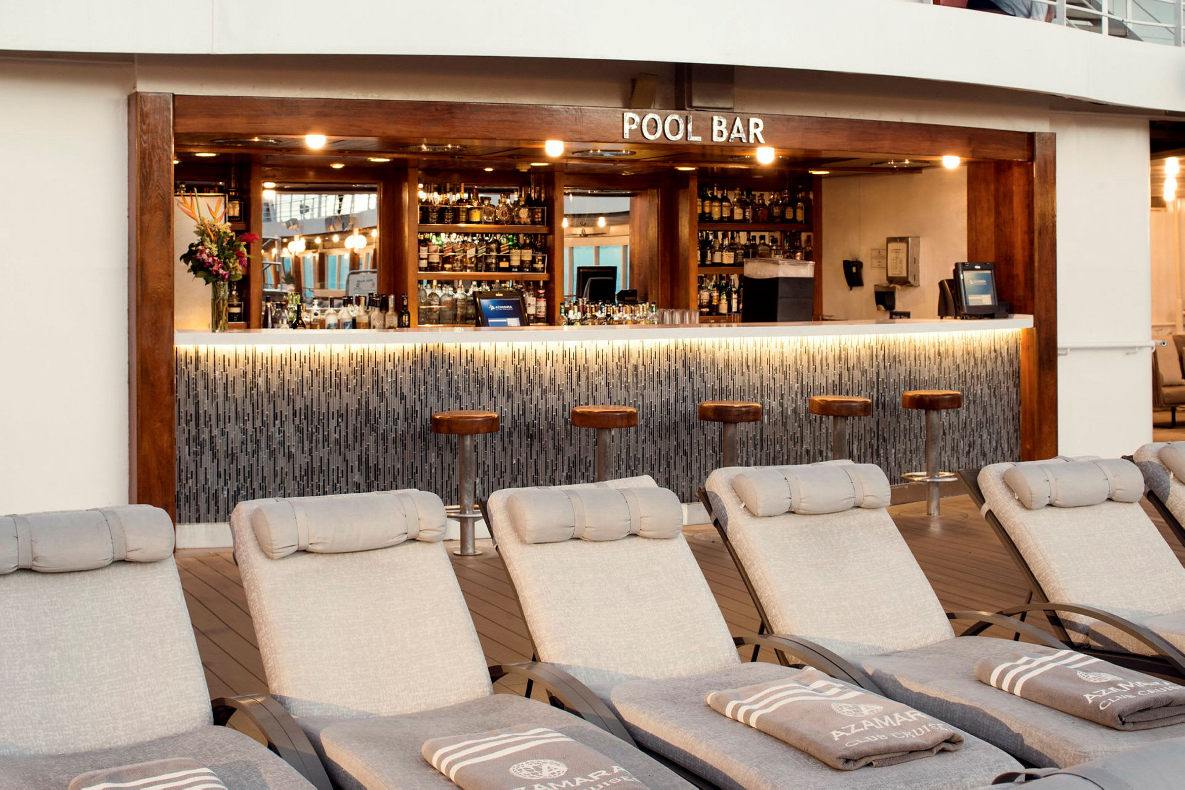 En poolbar med fyra barstolar framför en bardisk och solstolar i förgrunden. (AI-genererad text)