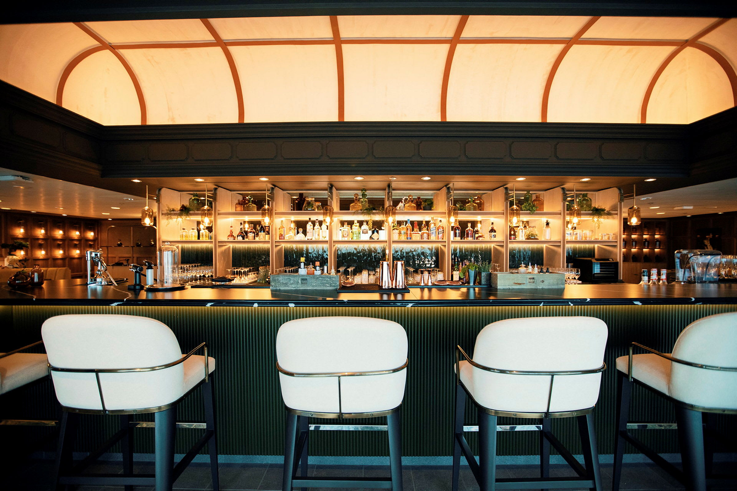 En elegant bar med designade stolar, välfyllda hyllor och stilfull belysning. (AI-genererad text)