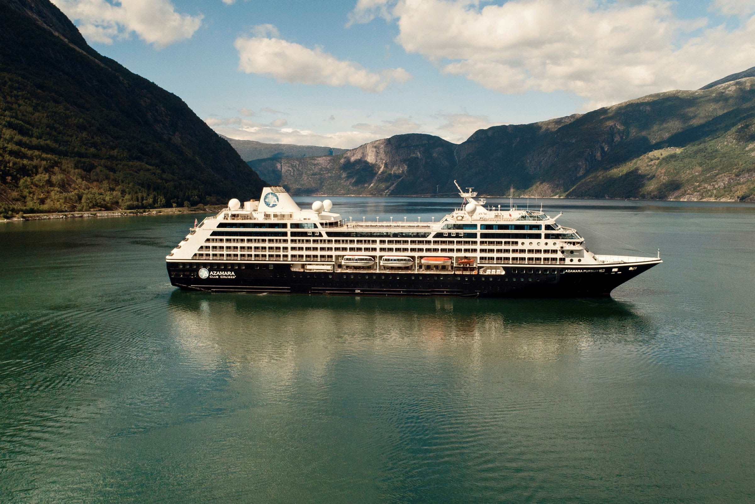 Ett kryssningsfartyg seglar genom en fjord omgiven av höga berg. (AI-genererad text)