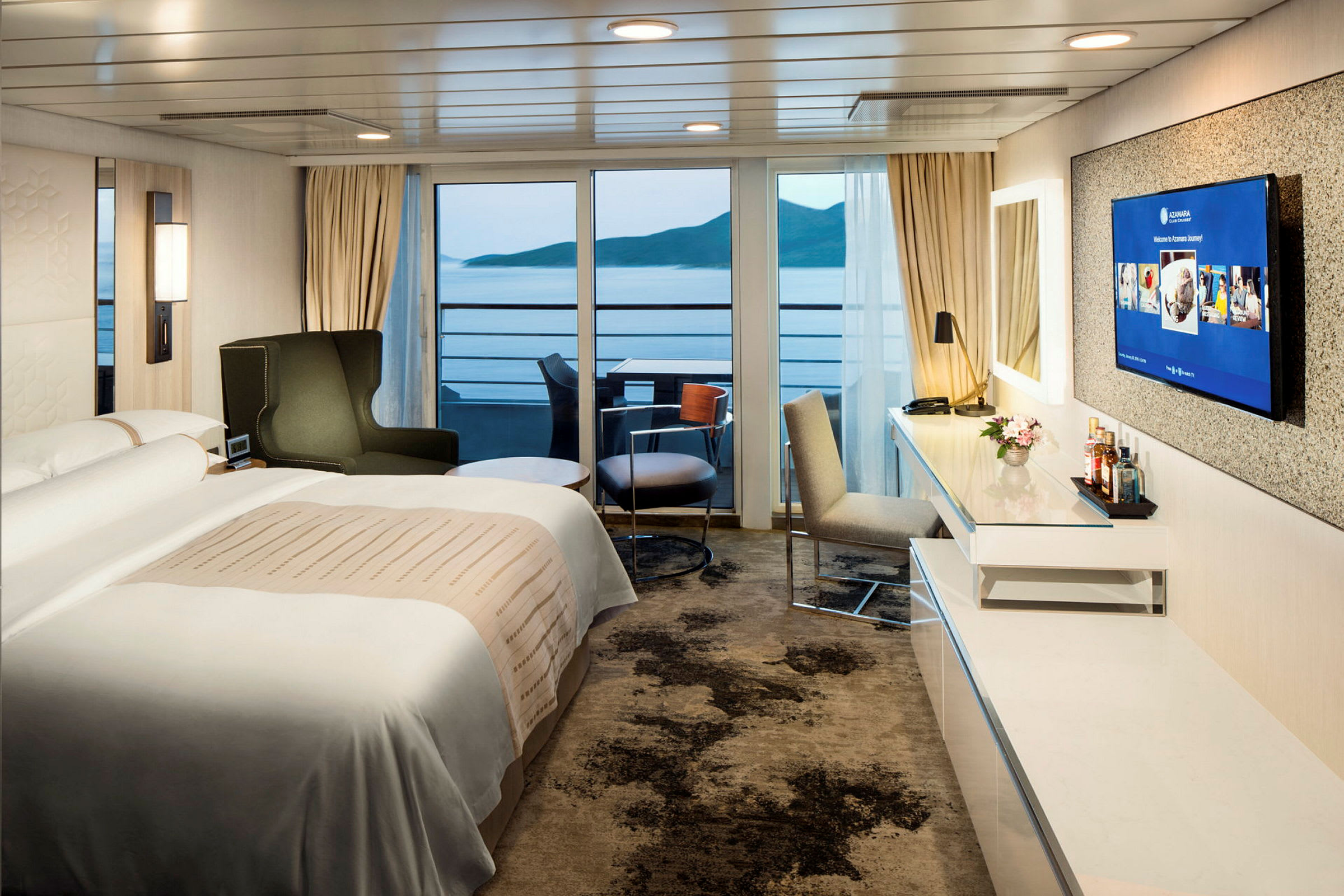 Ett modernt hotellrum med en dubbelsäng, sittplatser och en balkong med utsikt över havet. (AI-genererad text)