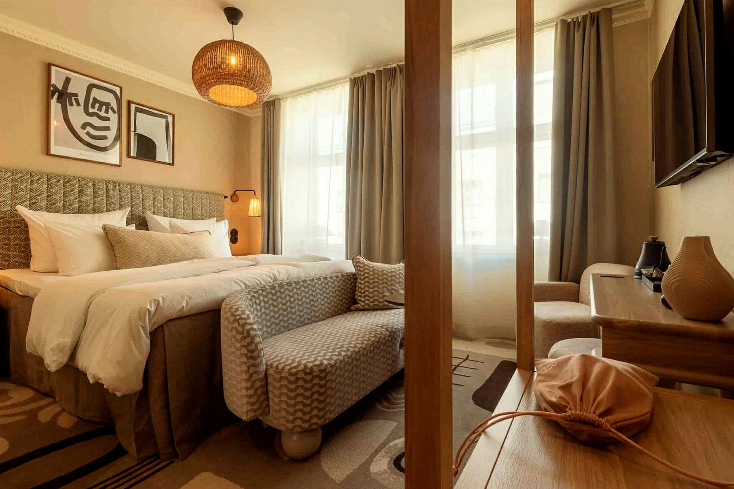 Ett välmöblerat hotellrum med en stor säng, en sittmöbel, ett bord och väggdekorationer. Fönstren är täckta med gardiner. (AI-genererad text)