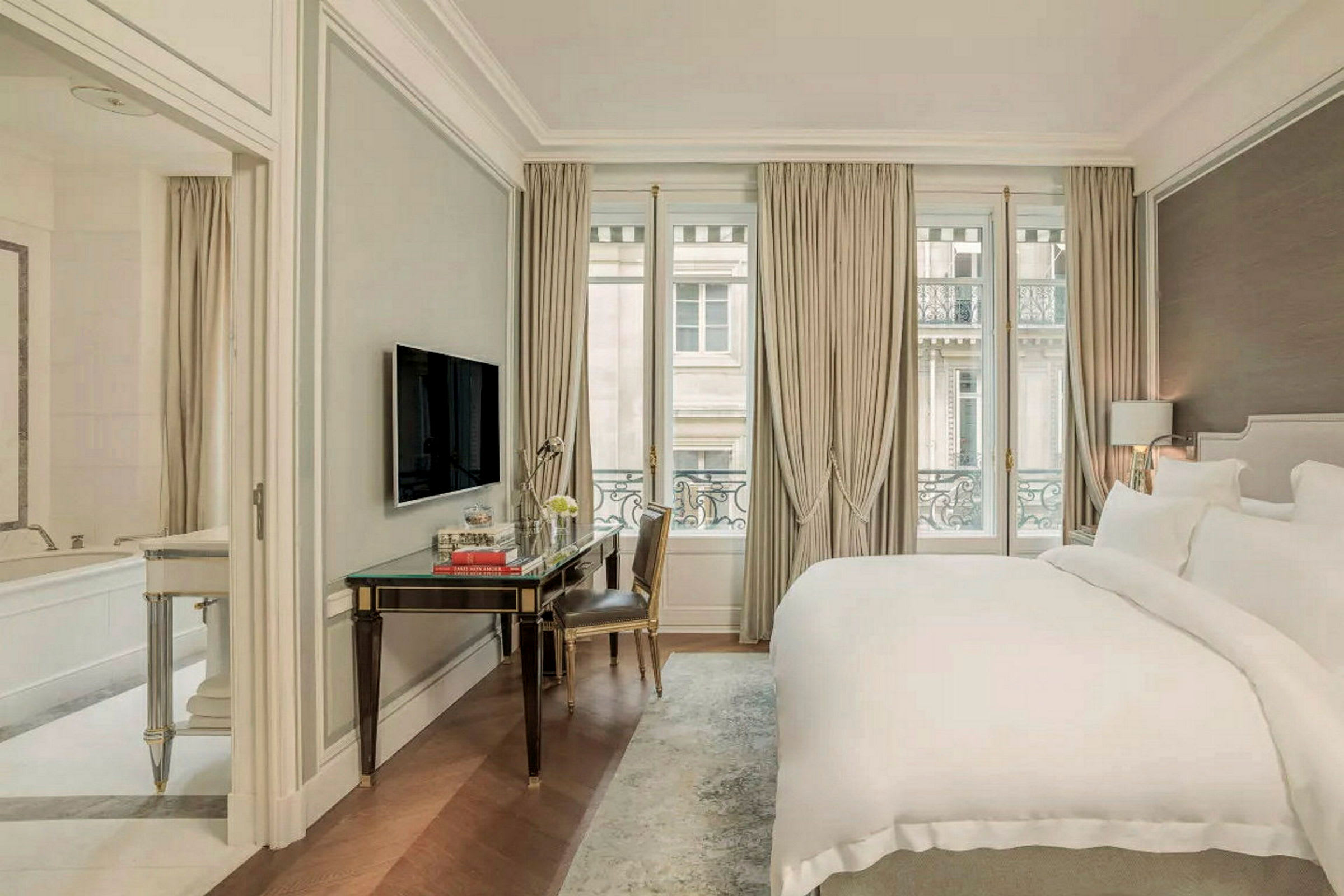 Ett elegant hotellrum med en stor säng, ett skrivbord, och ett fönster med gardiner. (AI-genererad text)