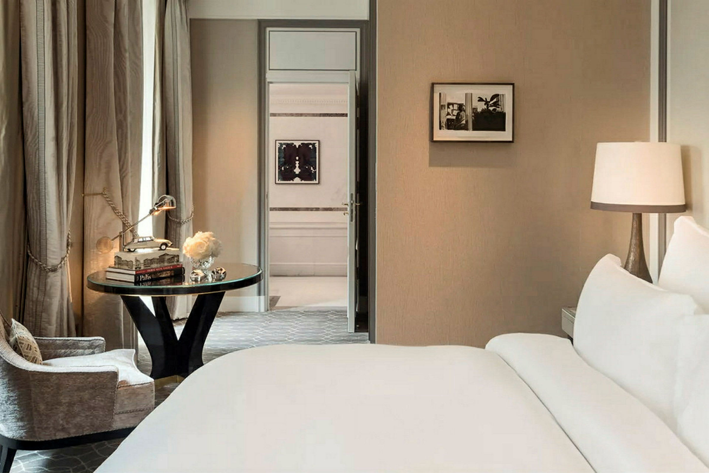 Ett elegant hotellrum med en stor säng, ett skrivbord och stolar. (AI-genererad text)