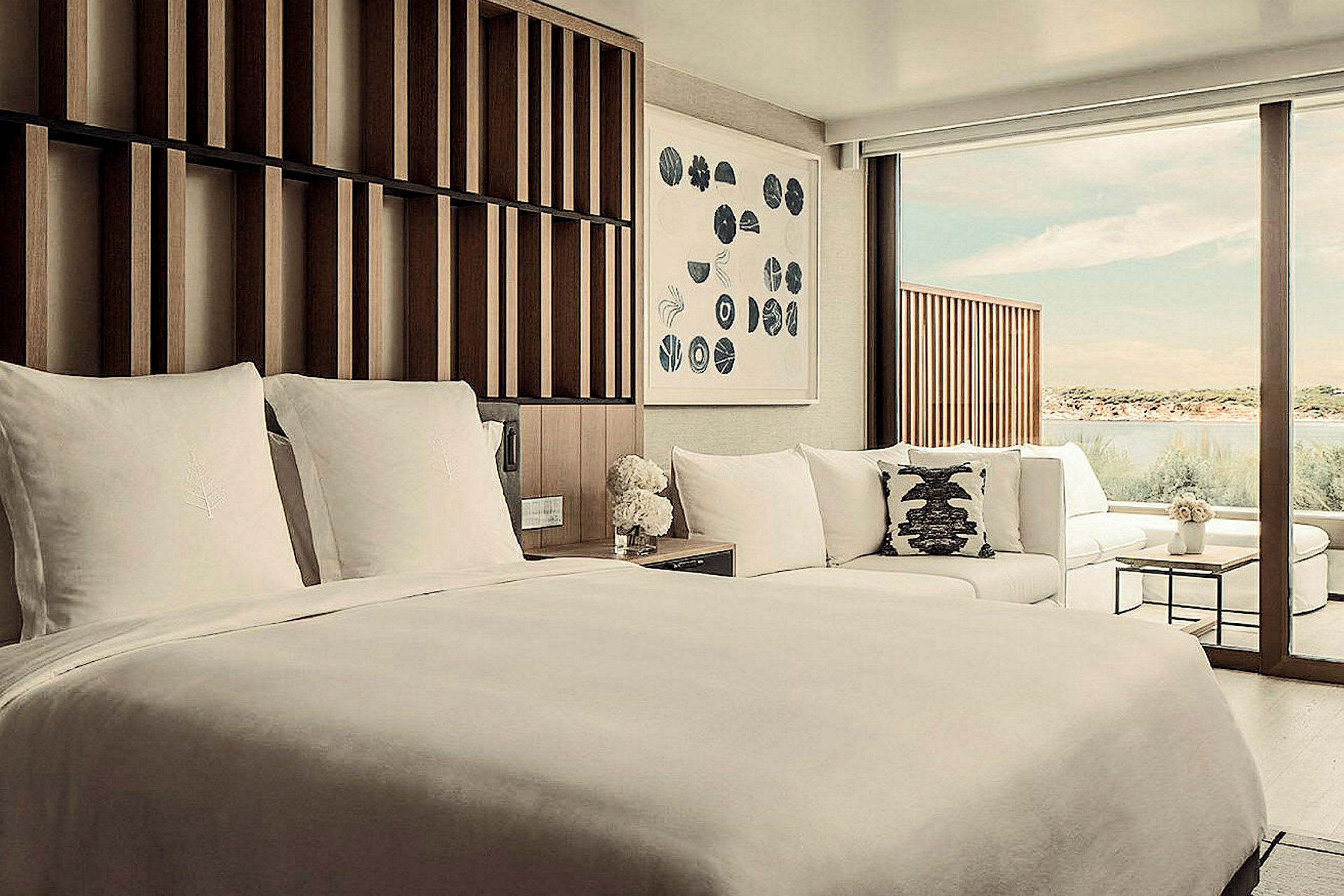 Ett hotellrum med en stor säng, soffa och fönster som vetter mot vatten. (AI-genererad text)
