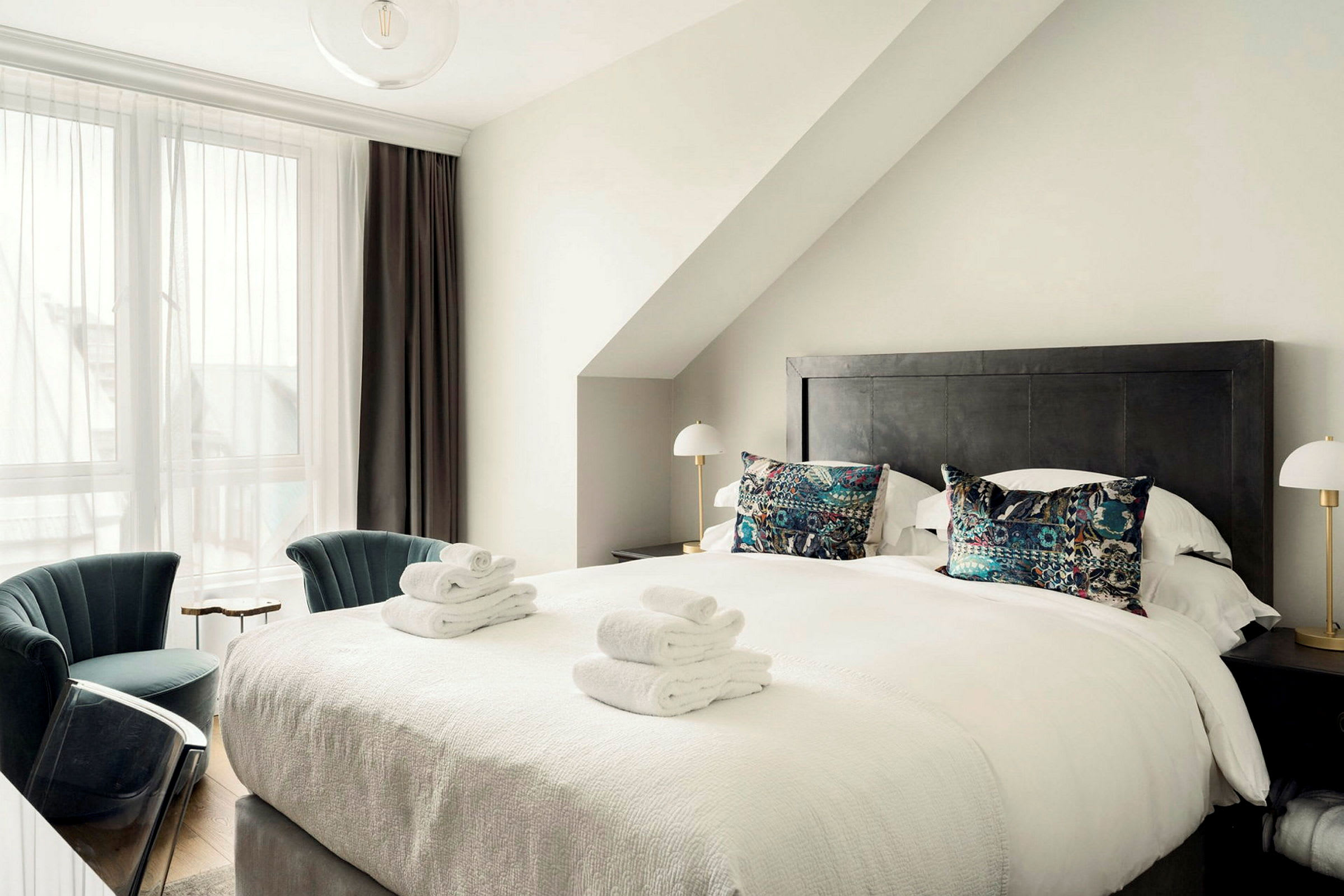 Ett hotellrum med en stor säng, dekorativa kuddar och vikta handdukar på täcket. (AI-genererad text)
