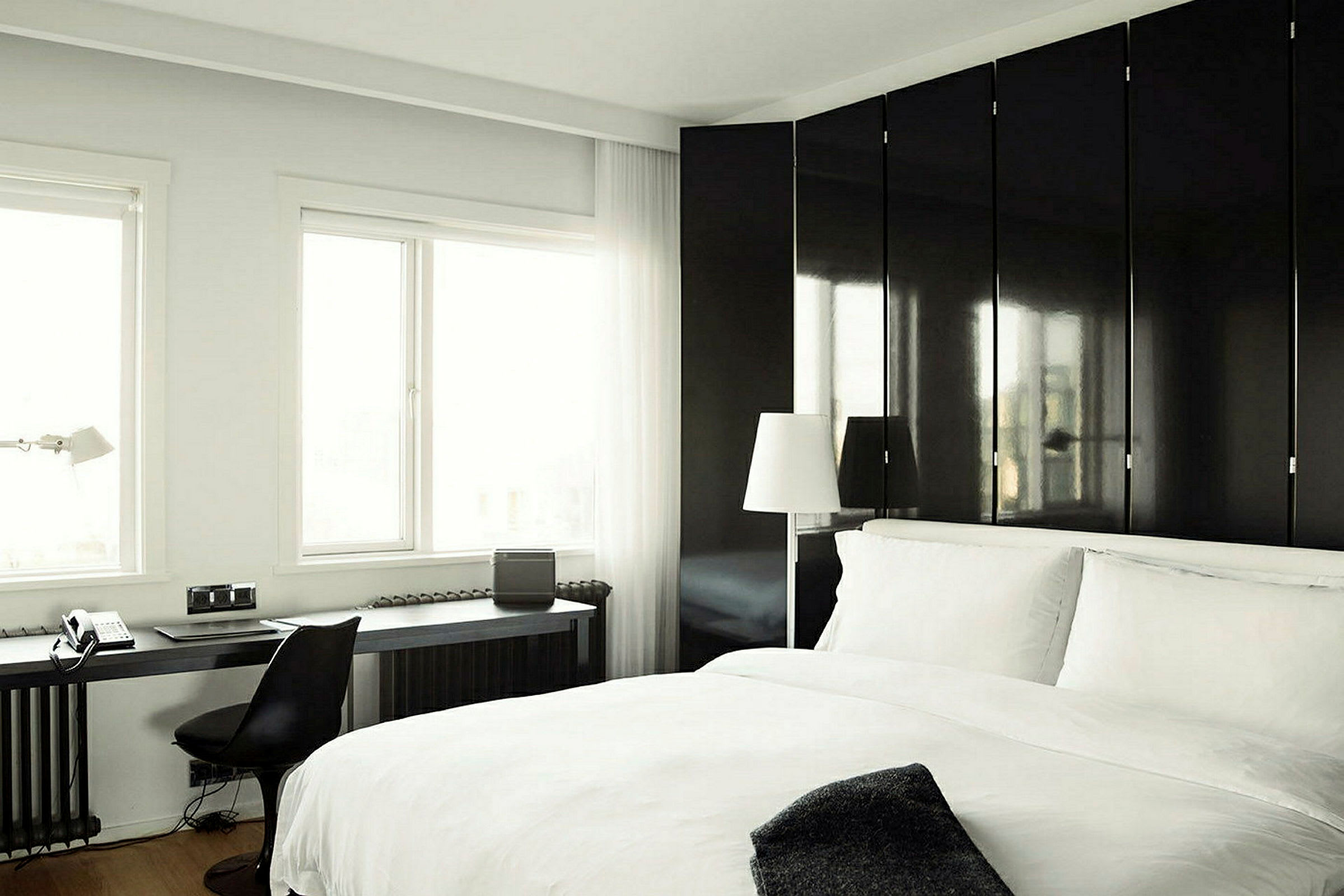 Modernt hotellrum med dubbelsäng, skrivbord och fönster med dagsljus. (AI-genererad text)