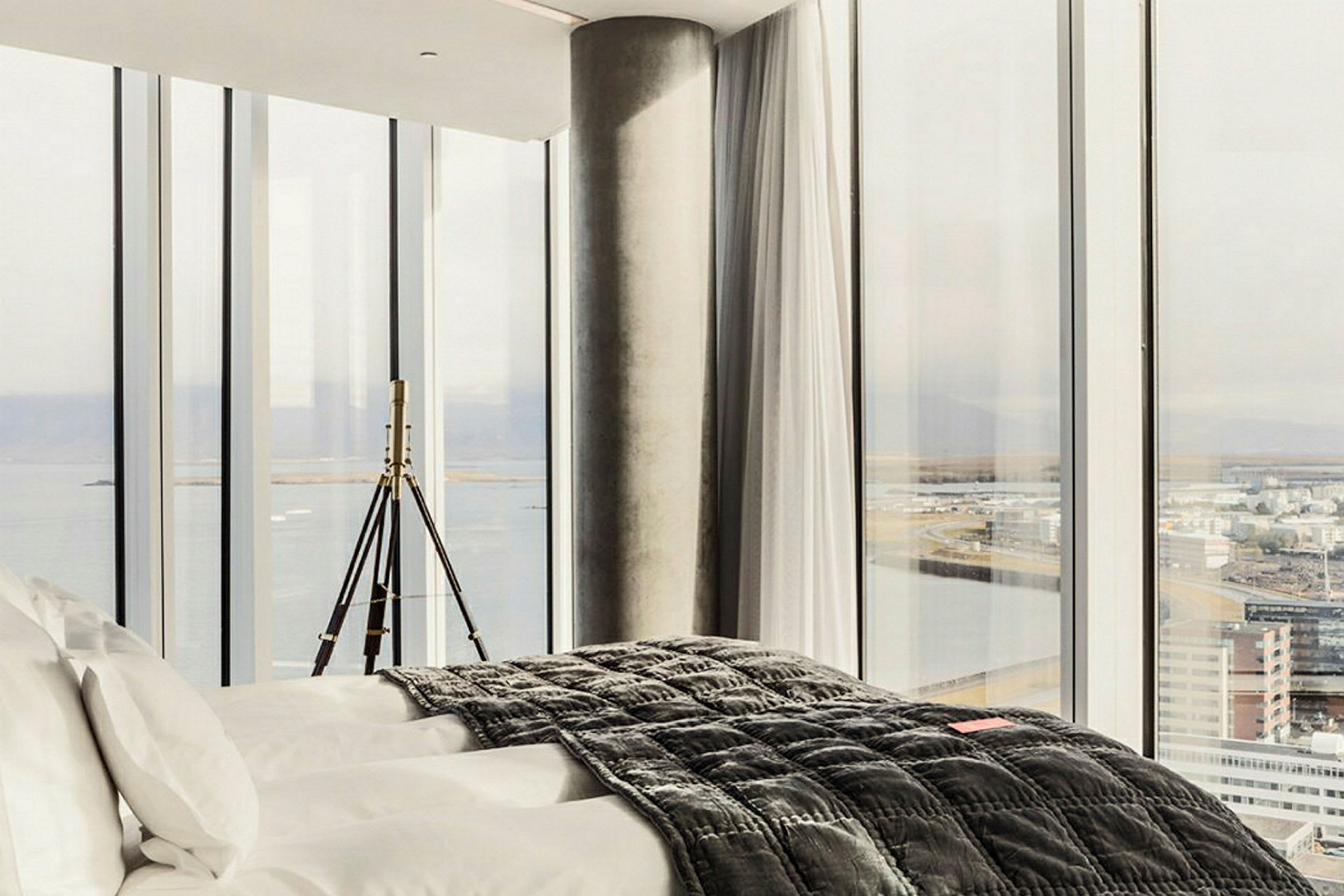 Hotellrum med inredning i modern design och stora fönster med utsikt över staden och havet. (AI-genererad text)