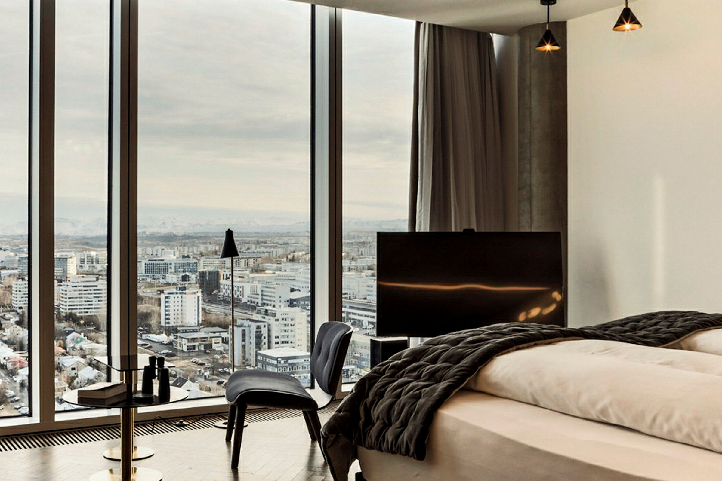 Ett modernt hotellrum med stora fönster som visar en stadsutsikt. (AI-genererad text)