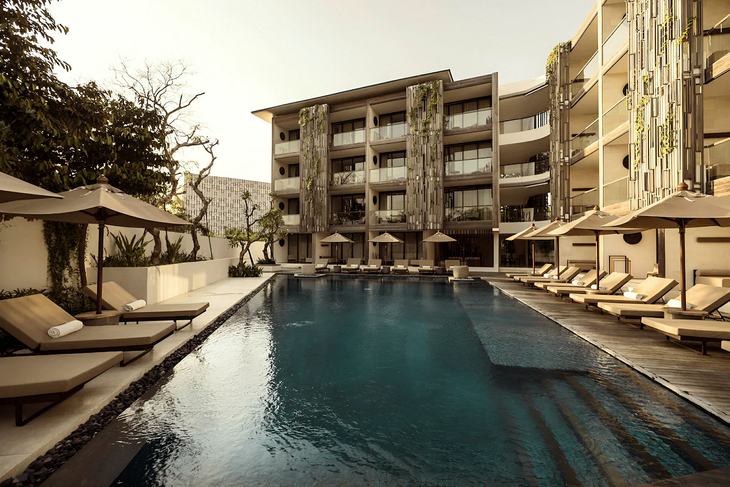 En swimmingpool omgiven av solstolar och parasoller vid ett modernt hotell. (AI-genererad text)