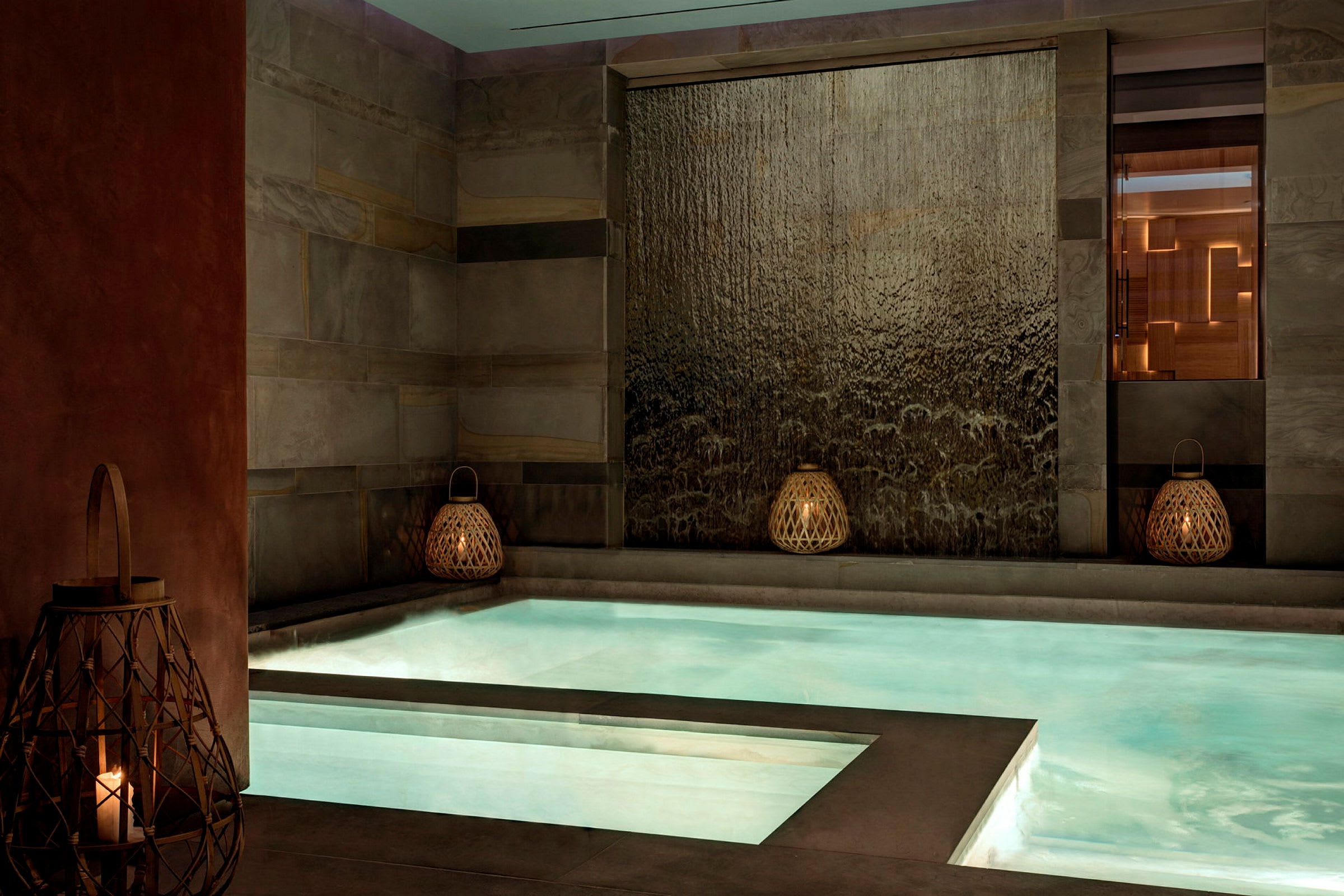 Modern pool med små belysningslyktor och vattenvägg. (AI-genererad text)