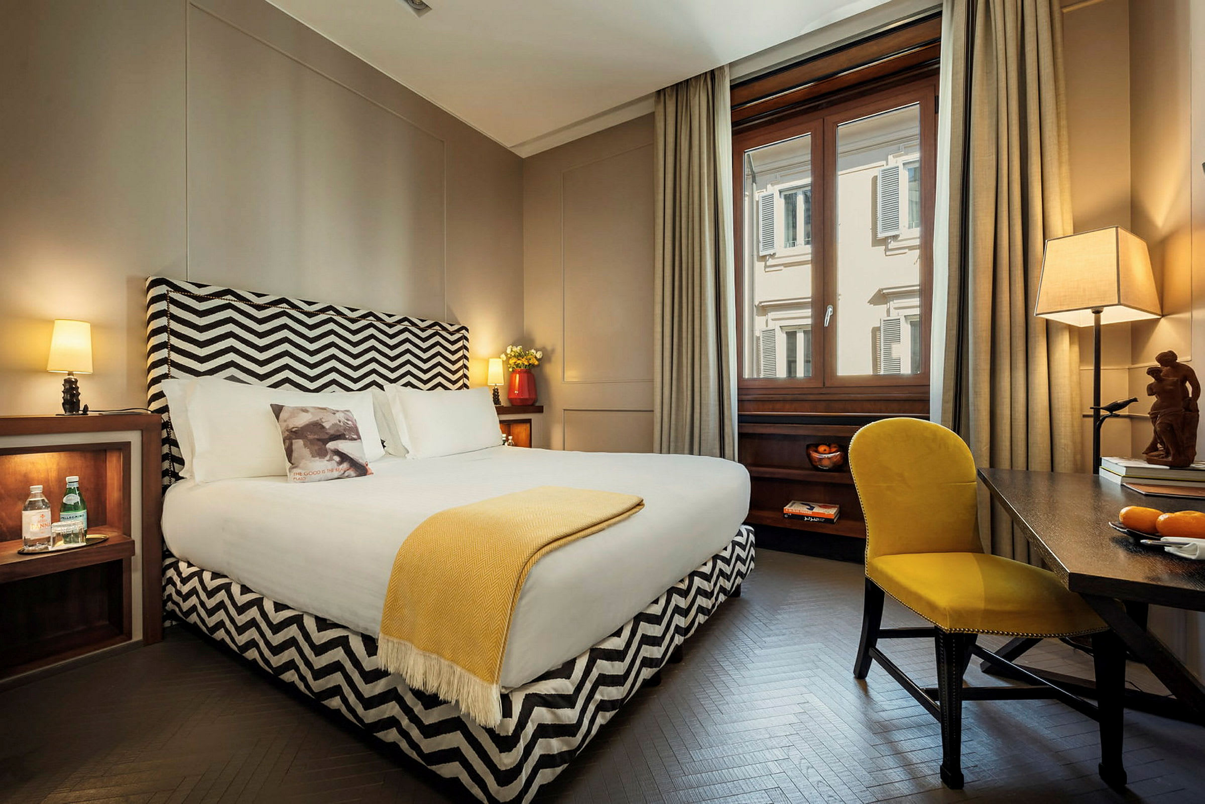 Ett stilfullt hotellrum med en stor säng, en fönsterutsikt och möblerade detaljer. (AI-genererad text)