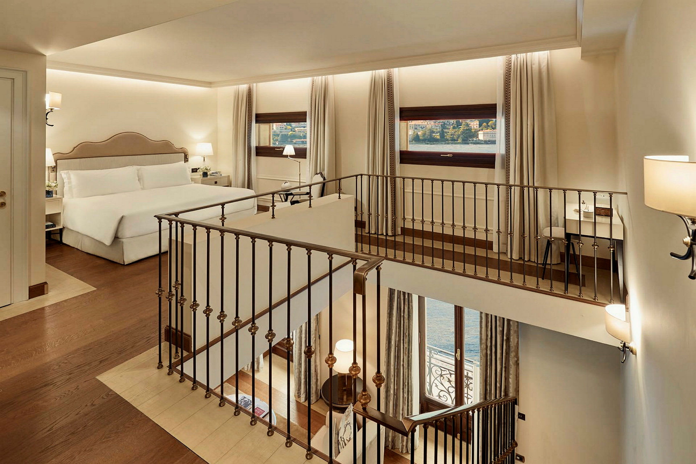 Bild på ett hotellrum med en dubbelsäng, fönster med utsikt mot vattnet och en inomhustrappa. (AI-genererad text)