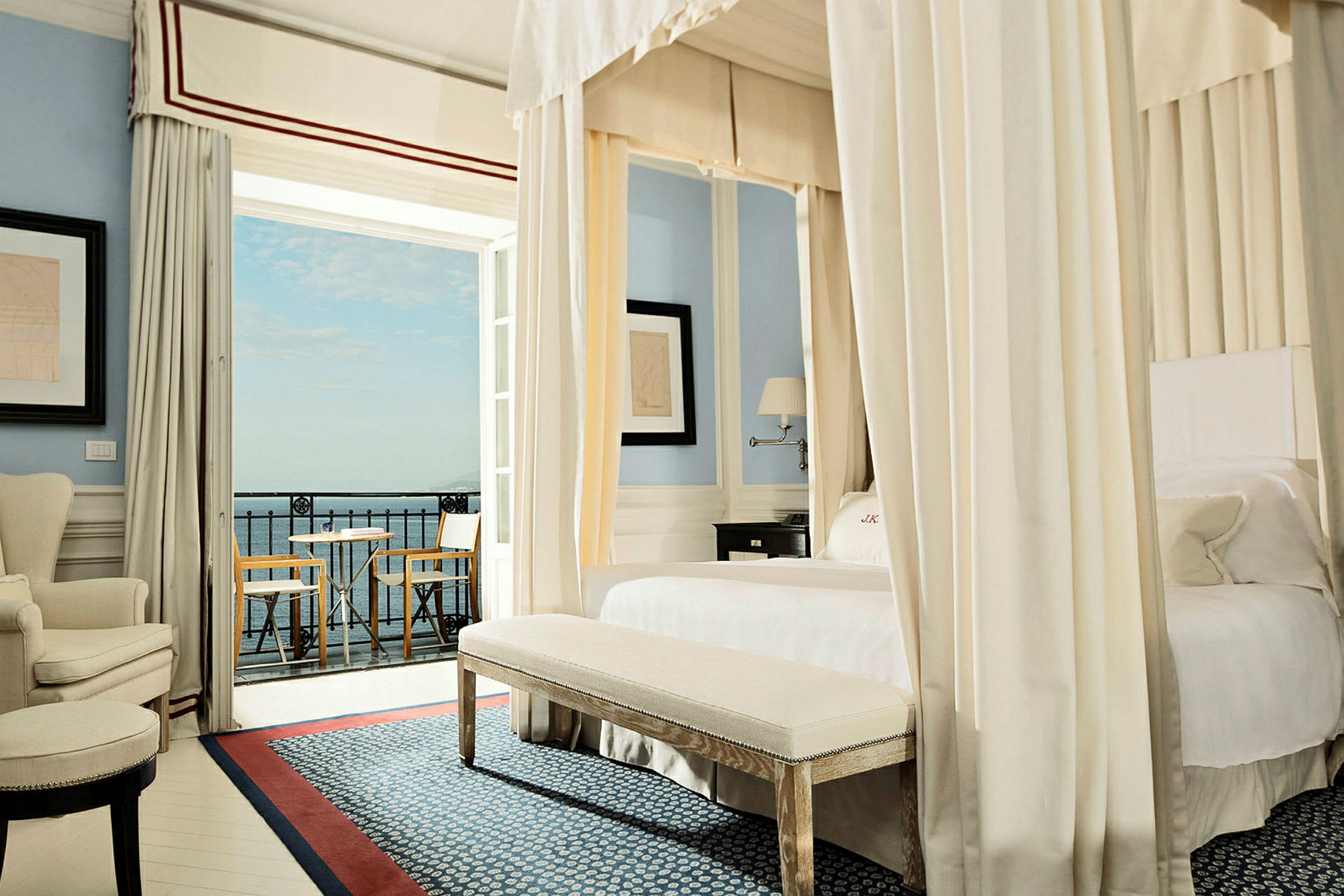 Ett elegant hotellrum med himmelssäng, sittmöbler och utsikt mot havet. (AI-genererad text)