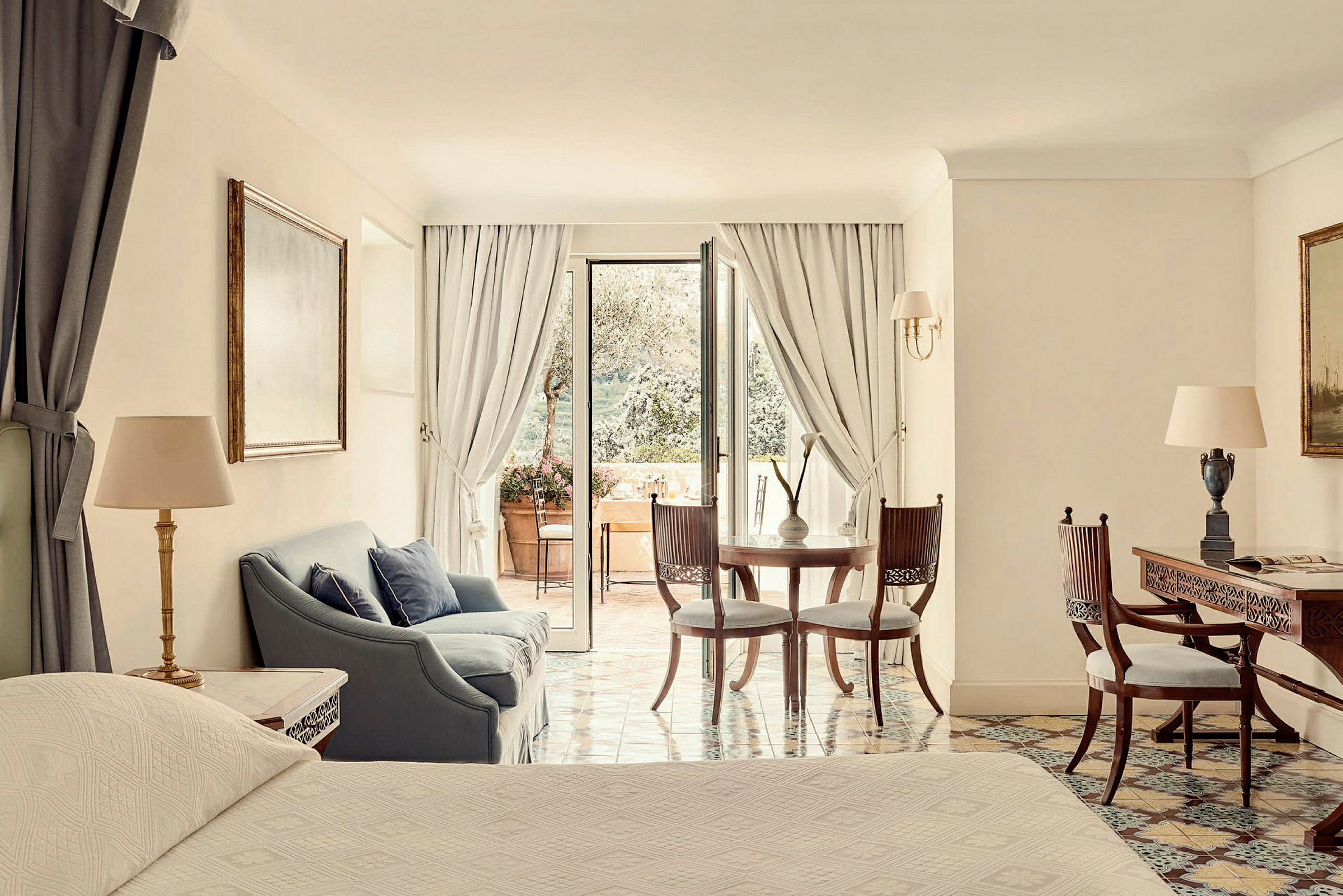 Ett elegant hotellrum med sittgrupp och utsikt mot en terrass. (AI-genererad text)