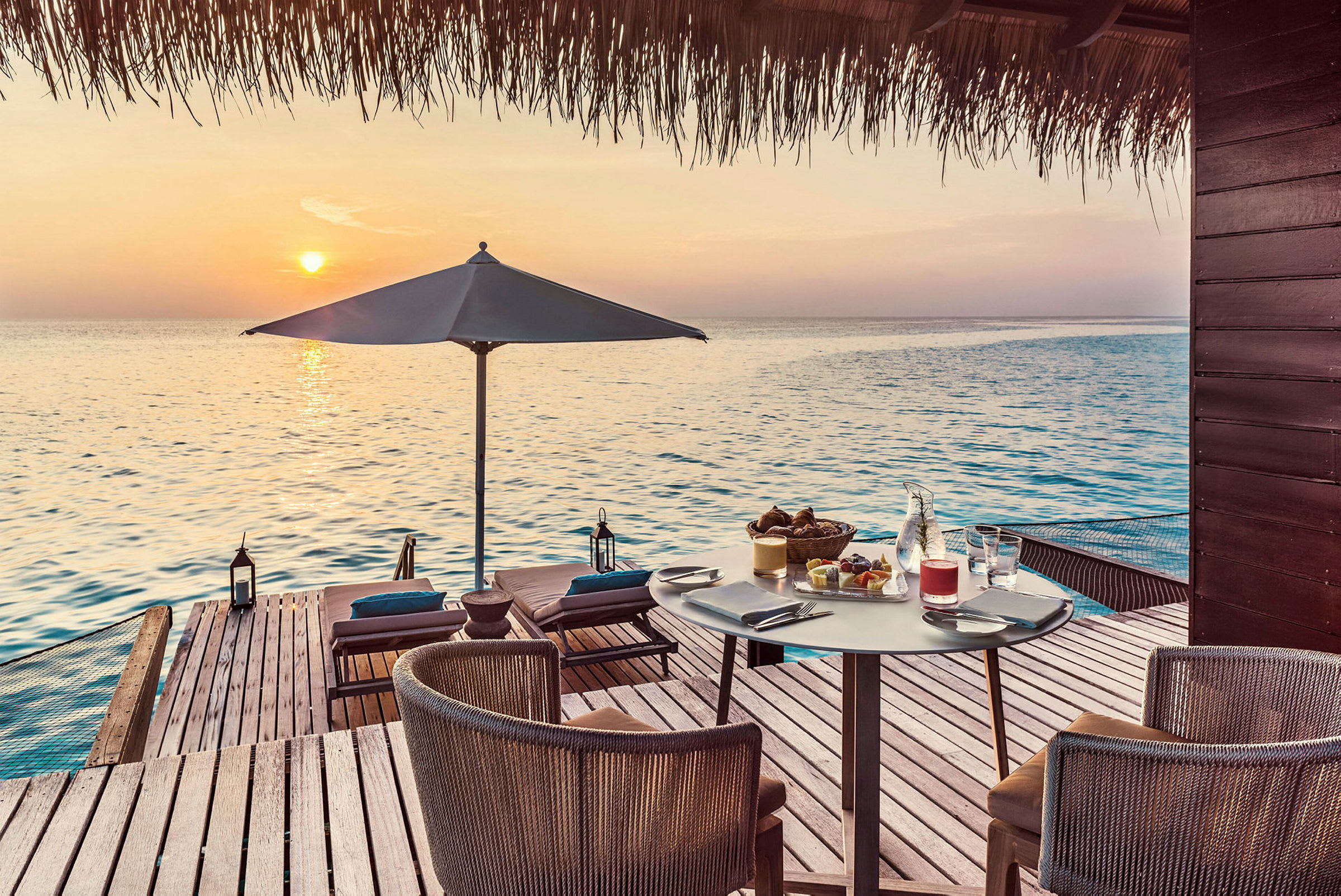 Utsikt över havet från en terrass med sittmöbler, parasoll och serverad frukost. (AI-genererad text)