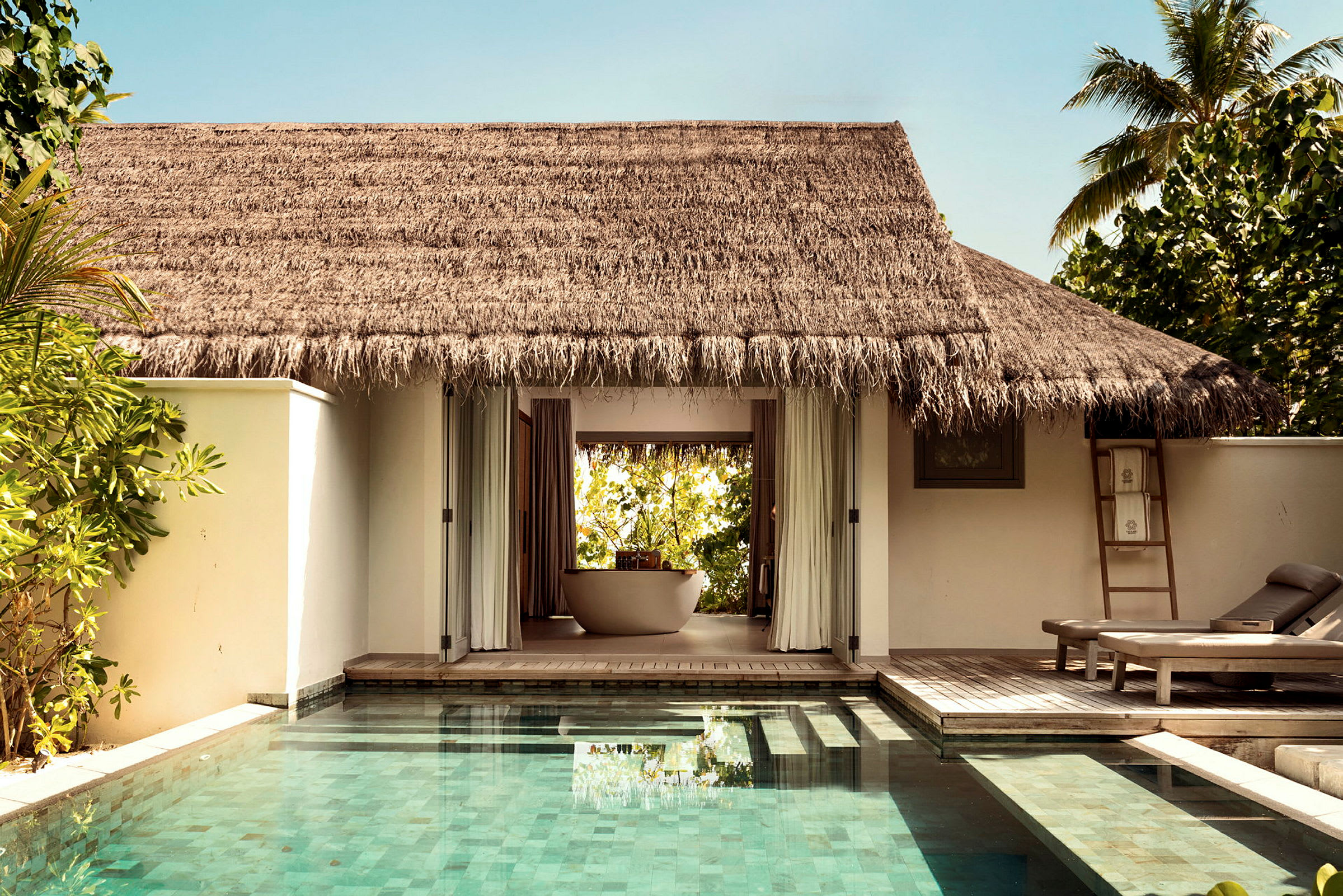 En bungalow vid sidan av en pool med terrass och solstolar. (AI-genererad text)