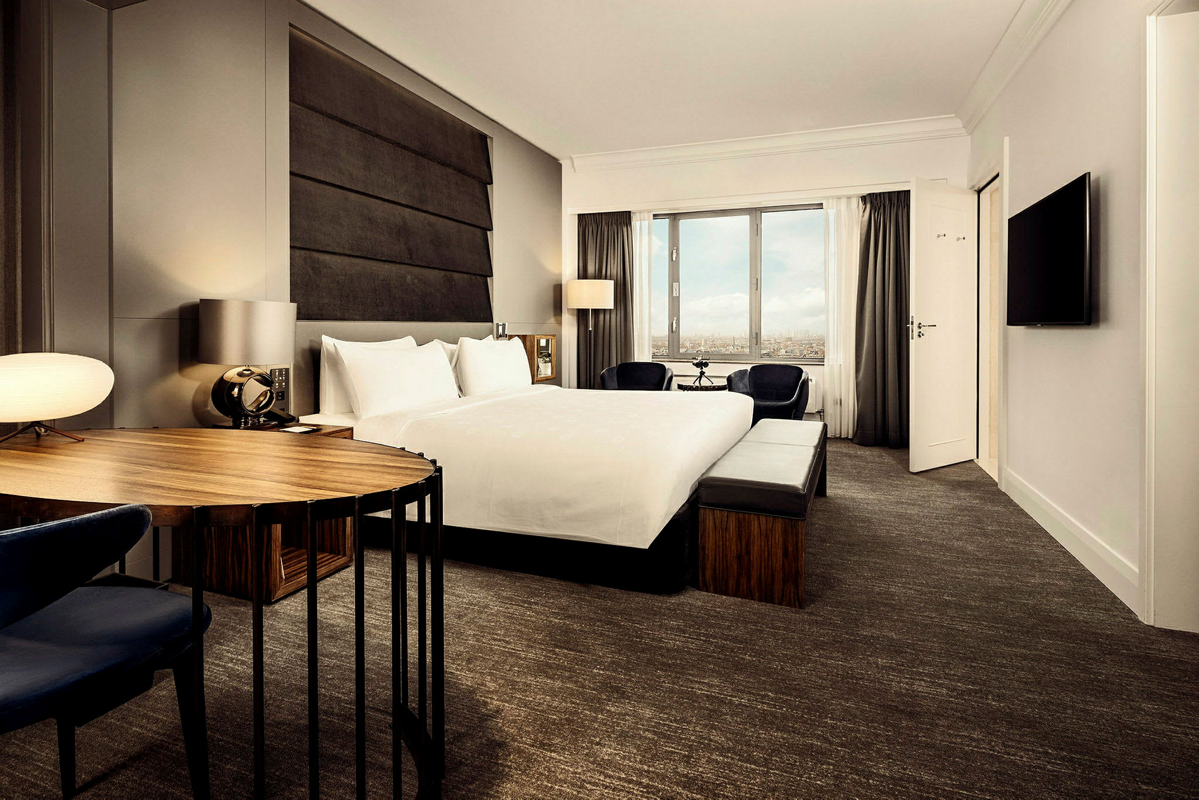 Ett modernt hotellrum med en stor säng, skrivbord och fönster. (AI-genererad text)