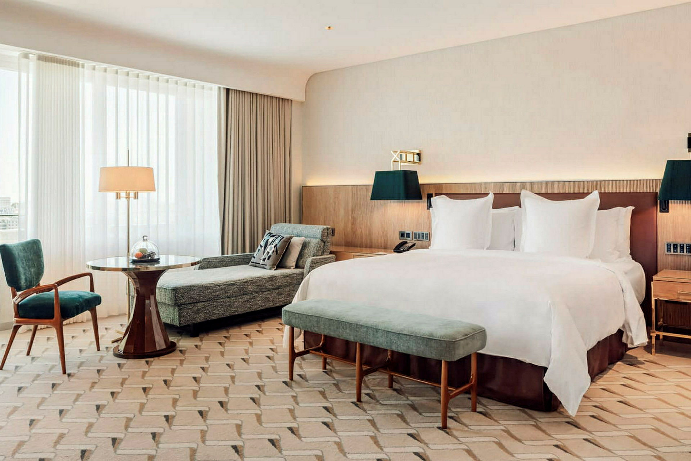 Ett hotellrum med en stor säng, en sittgrupp och naturligt ljus från ett stort fönster. (AI-genererad text)