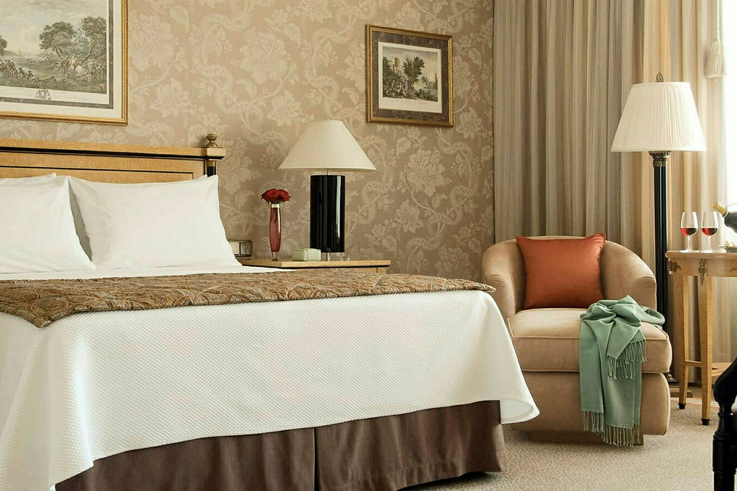 Hotellrum med säng, fåtölj och bord. (AI-genererad text)