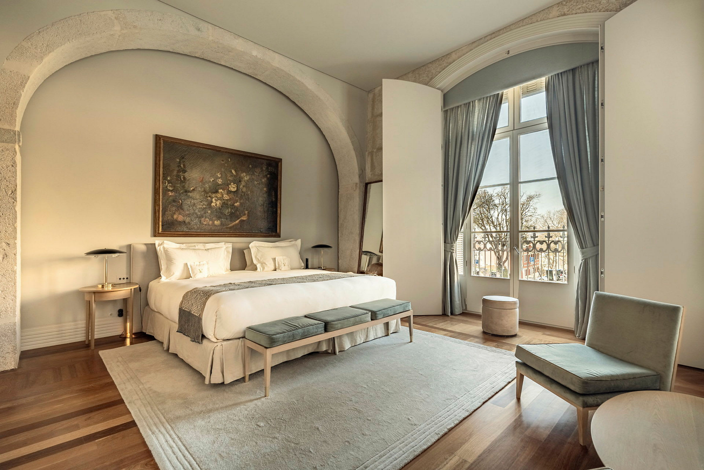 Ett elegant hotellrum med en stor dubbelsäng, sittmöbler och ett stort fönster med gardiner. (AI-genererad text)