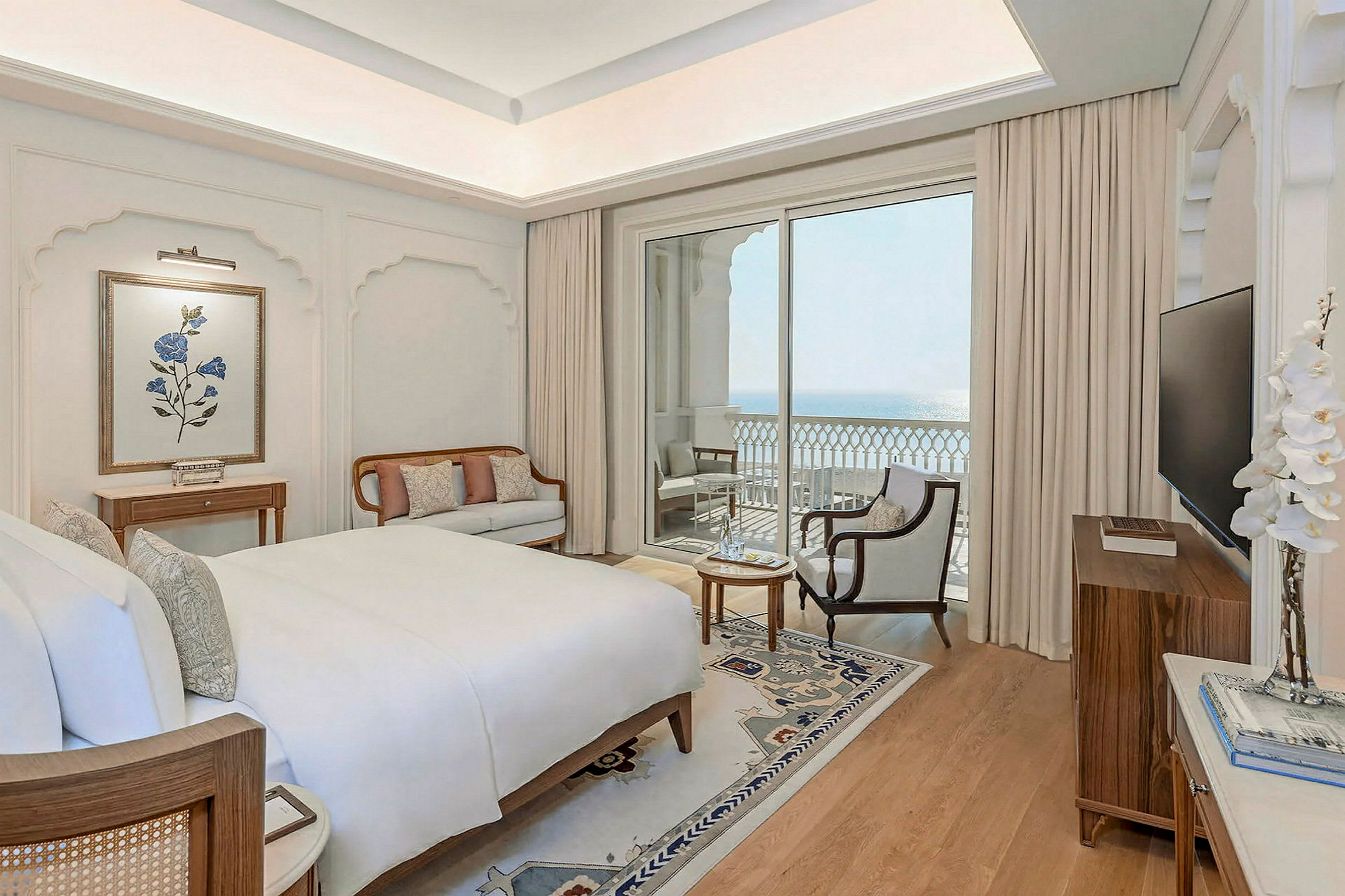 Ett elegant hotellrum med stor säng, sittmöbler och en balkong med havsutsikt. (AI-genererad text)
