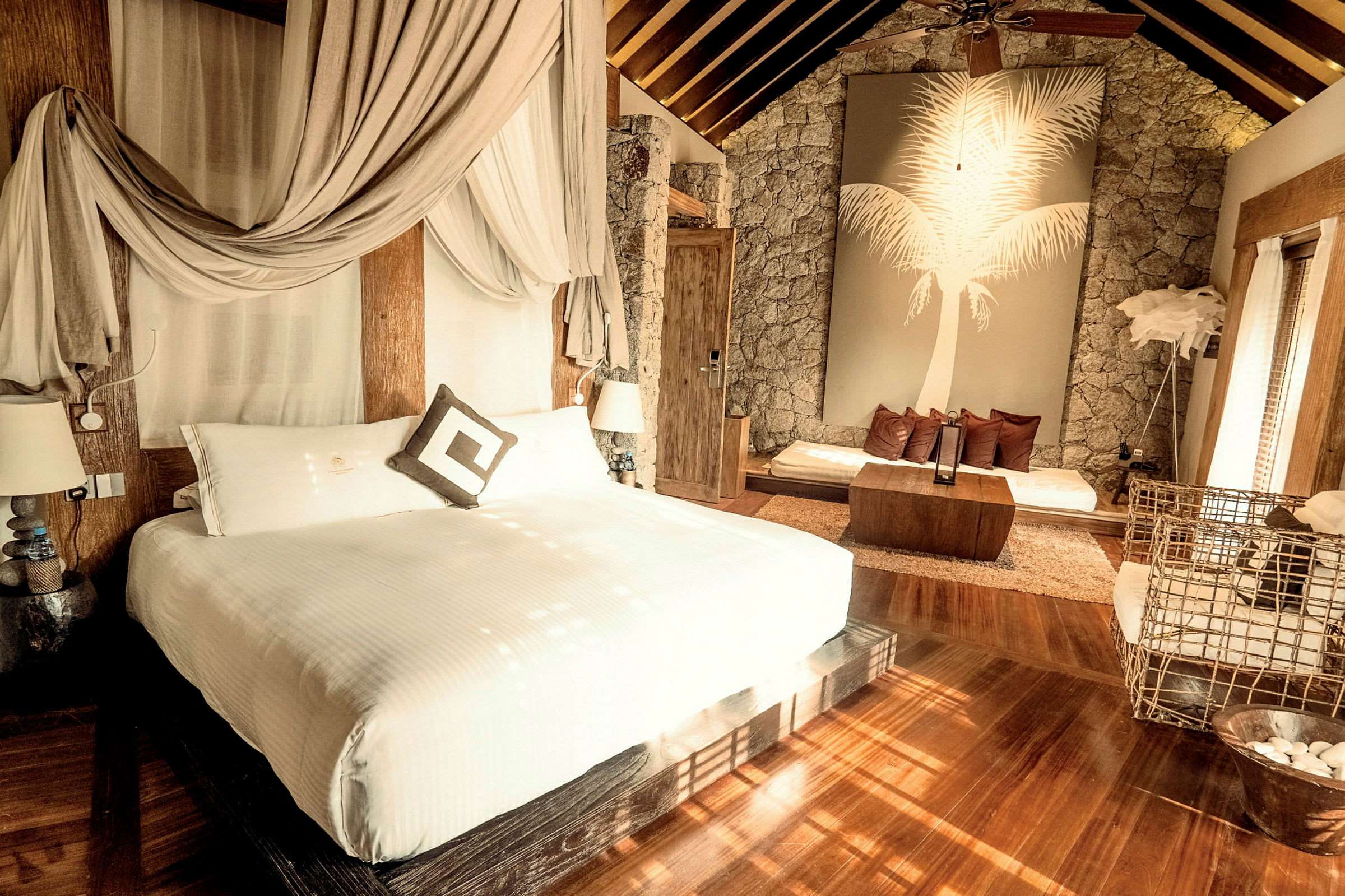 Elegant hotellrum med dubbelbädd, sittgrupp och dekorativ vägg med palmmotiv. (AI-genererad text)