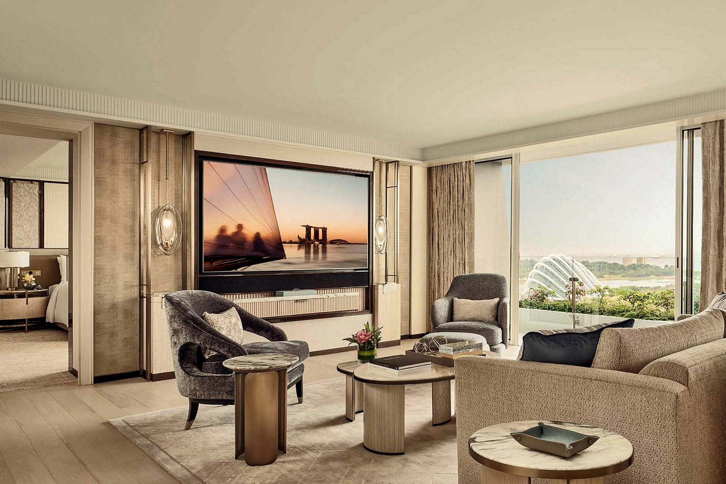 Ett elegant vardagsrum med moderna möbler, inklusive soffor och fotöljer, och en stor TV på väggen. Ett fönster visar utsikt över en trädgård och stadens silhuett. (AI-genererad text)