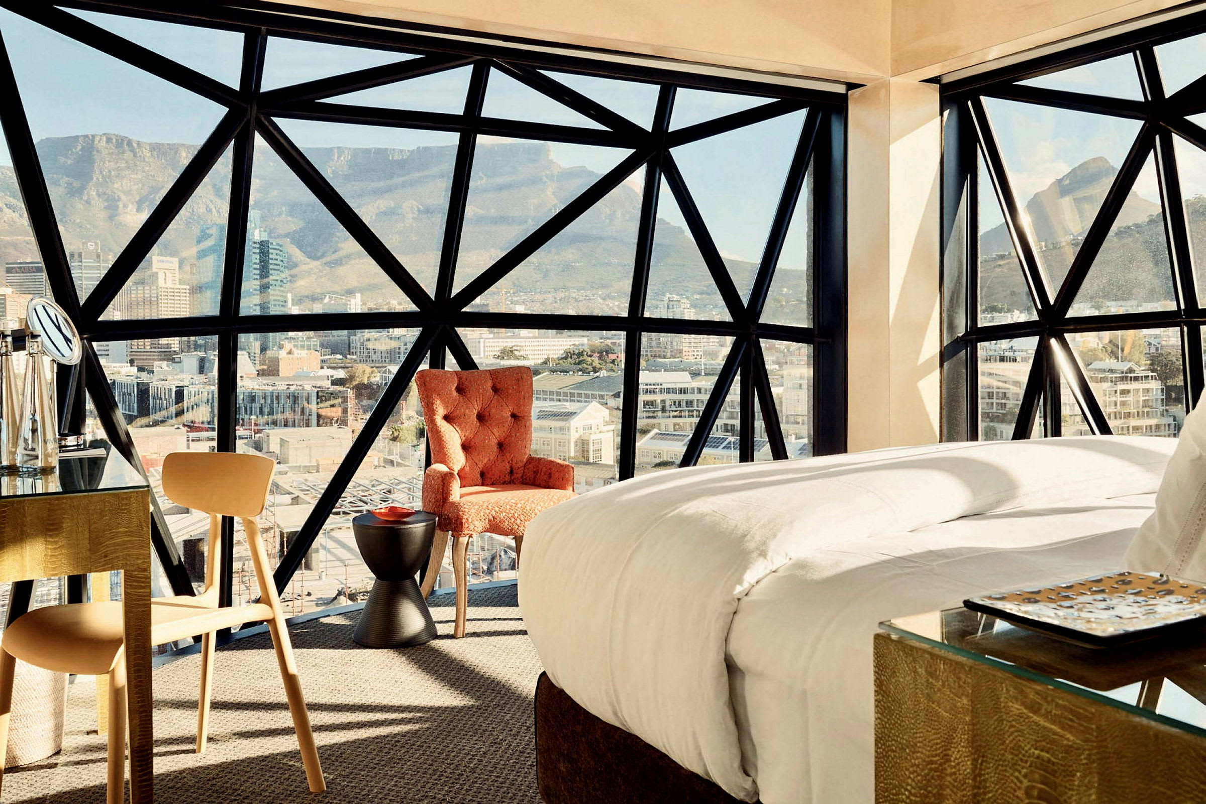 En hotellsvit med modern inredning och stora fönster med utsikt över berg och stad. (AI-genererad text)