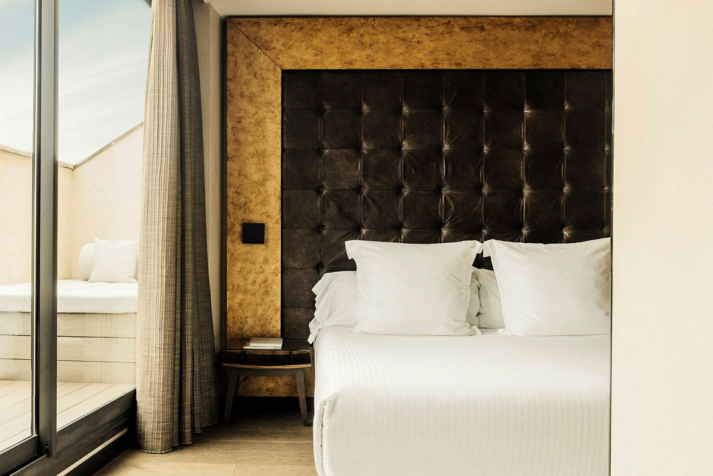 Hotellrum med en säng med vit sängkläder och en vadderad sänggavel. (AI-genererad text)