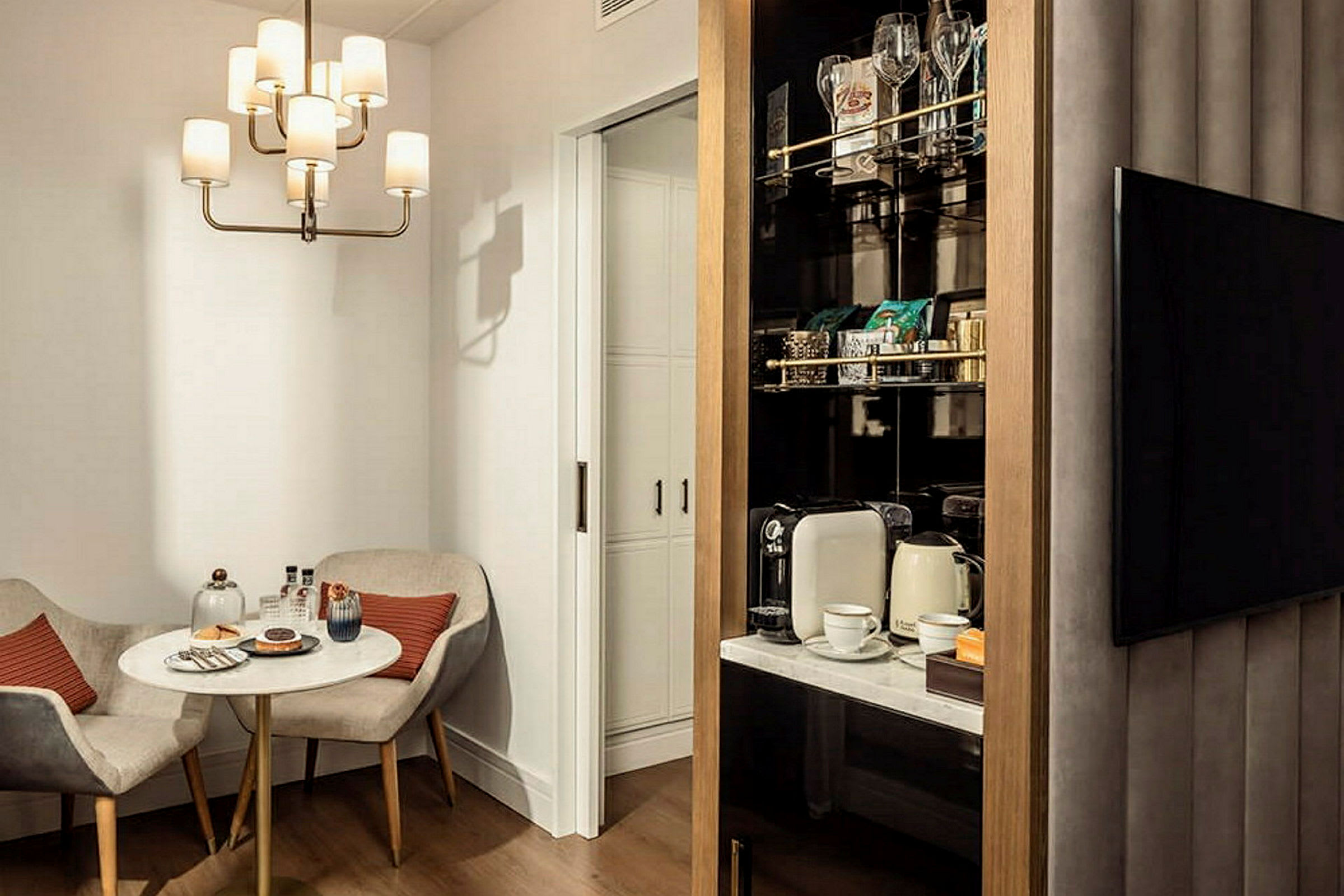Ett elegant rum med ett litet bord, två stolar, och en minibar med kaffeutrustning. (AI-genererad text)